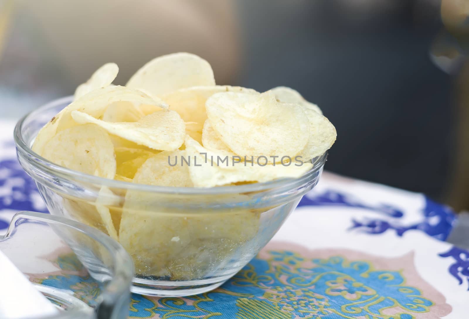 potato chips inside a glass bowl on a bar table. Appetizer and junk food