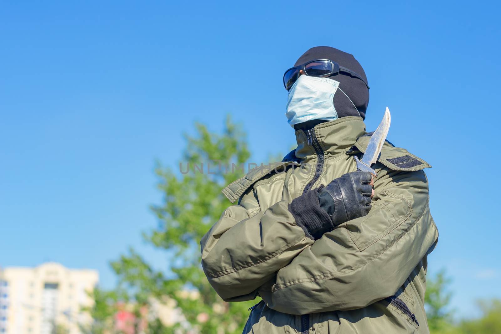 Soldier in medical mask and sunglasses against the sky