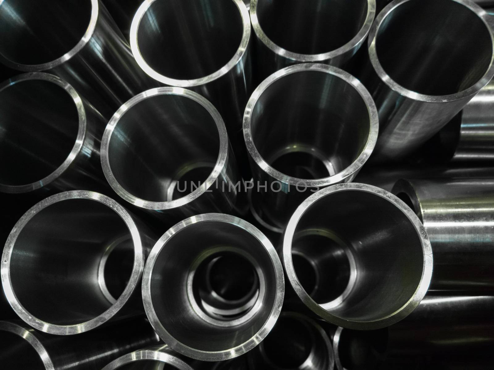 dark industrial background with cnc machined shiny steel pipes - selective focus and lens blur technique