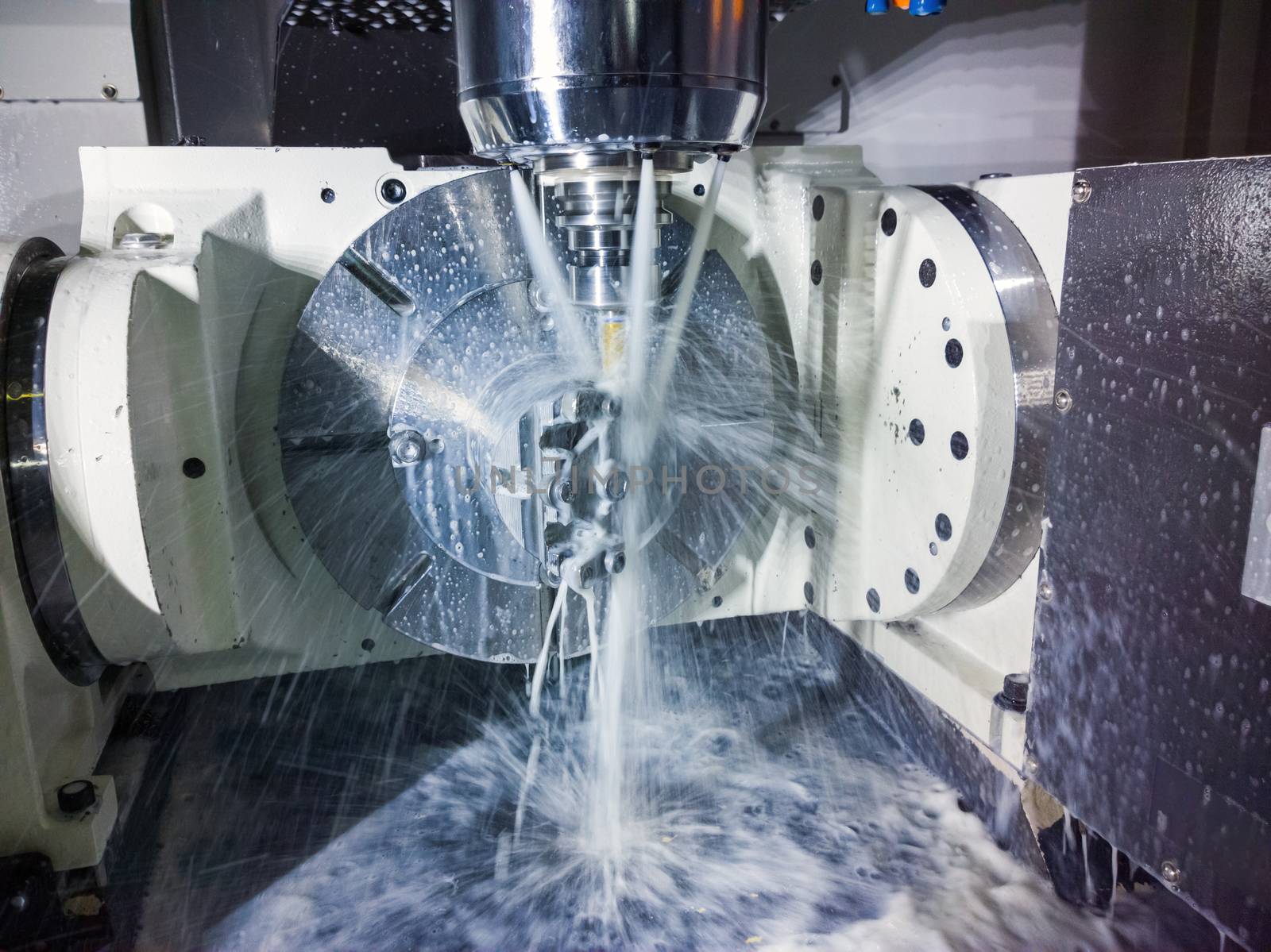 5-axis cnc milling machine at work with coolant under pressure. Table-table type of machine's kinematics. Natural motion blur of coolant streams and real capture technique.