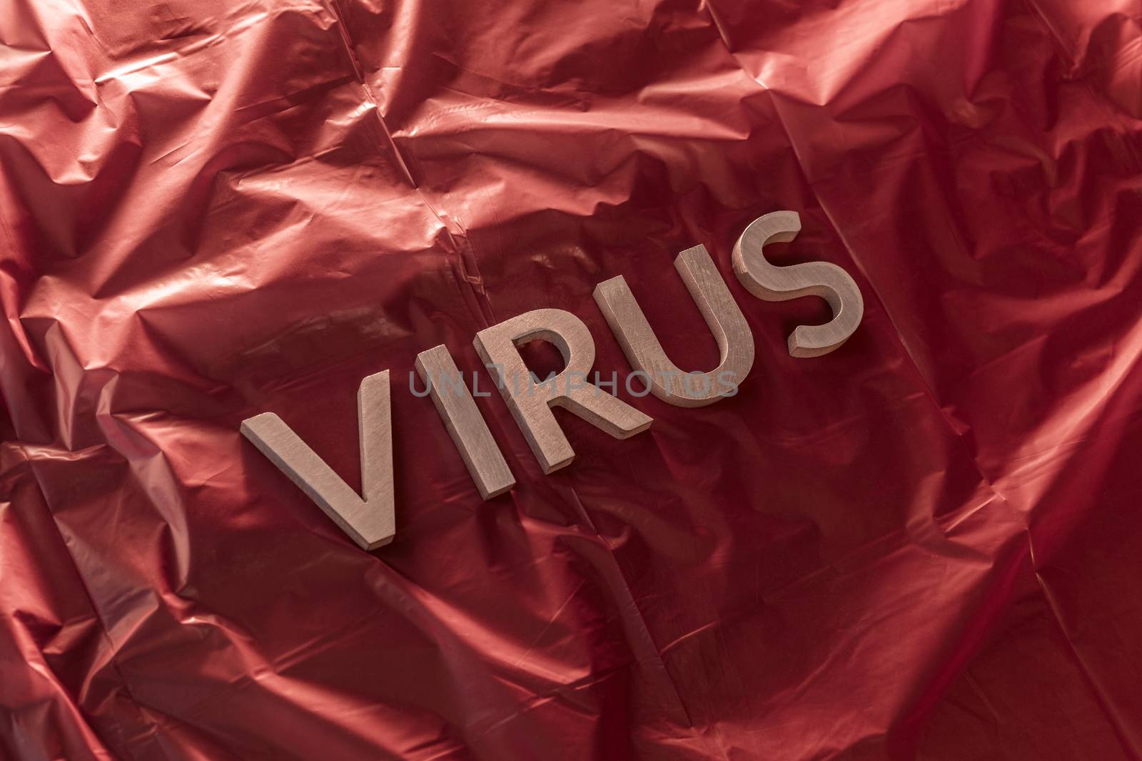 the word virus laid with brushed silver metal letters on crumpled red plastic film diagonal perspective composition and dramatic light