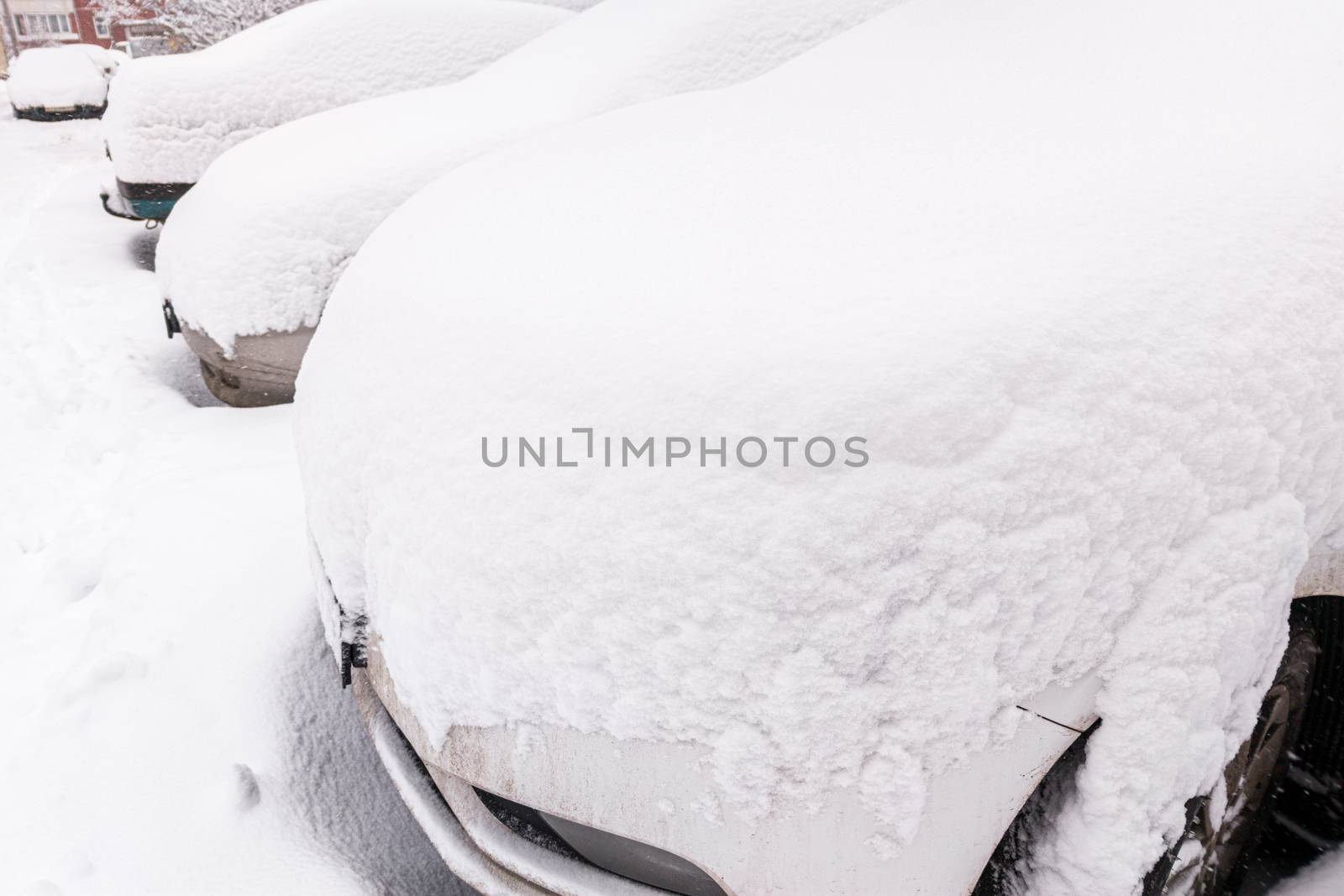 snow covered cars ofter blizzard at daylight parking - wide angle picture.