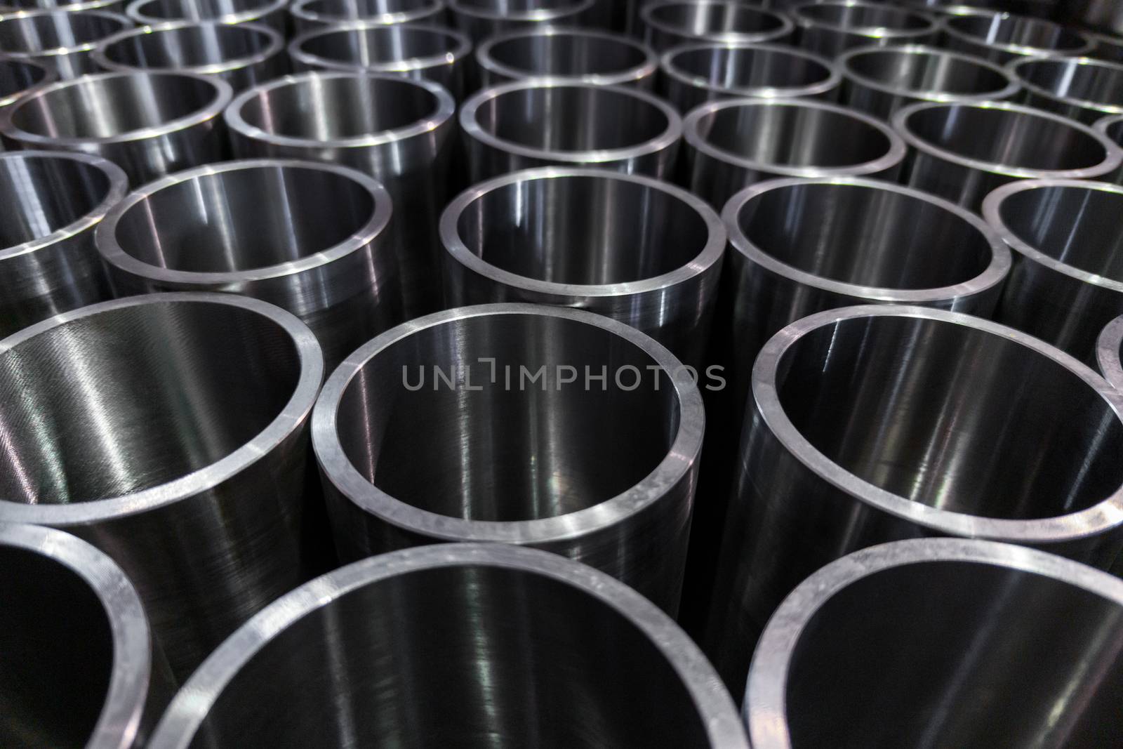 dark industrial background with cnc machined shiny steel pipes - selective focus and lens blur technique