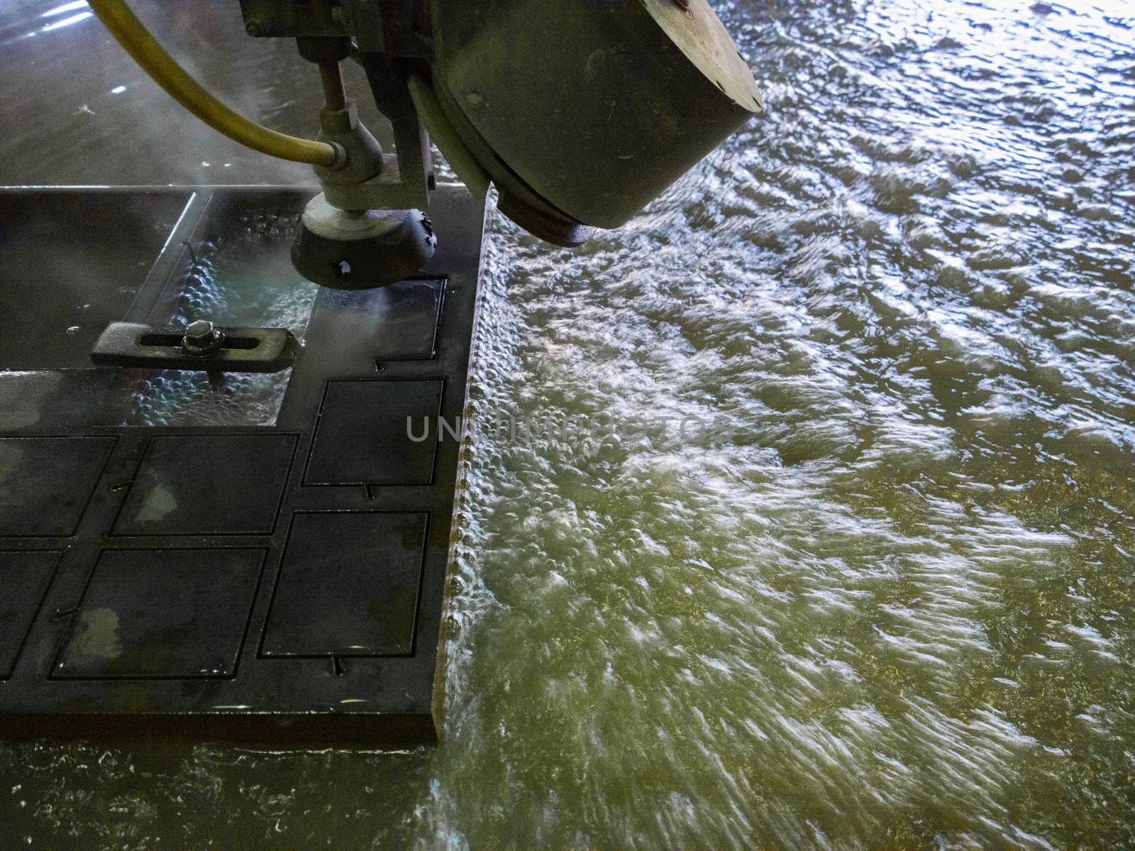 waterjet cutting process of thick black metal sheet.