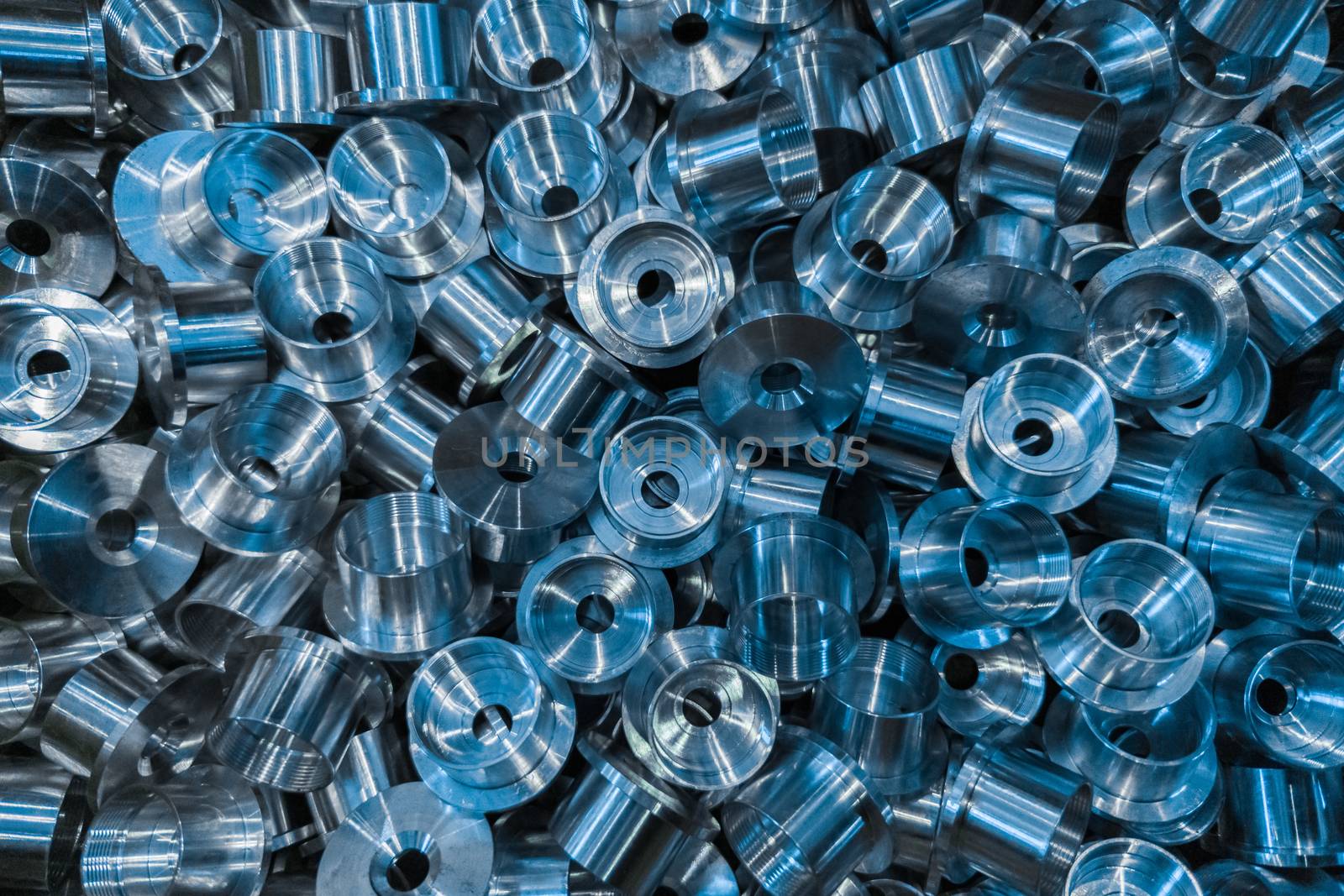 An industrial background with a pile of shiny metal cnc aerospace parts. Close-up full frame flat lay tech backdrop.