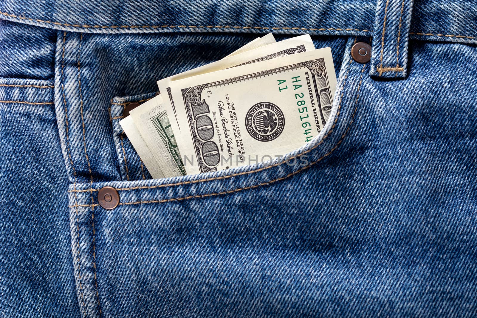 US dollar banknotes in the left front pocket of blue jeans. Concept of saving money or pocket expenses.