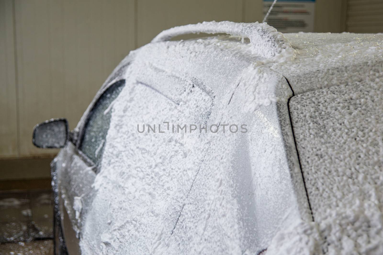 a car foam application process while washing indoors.