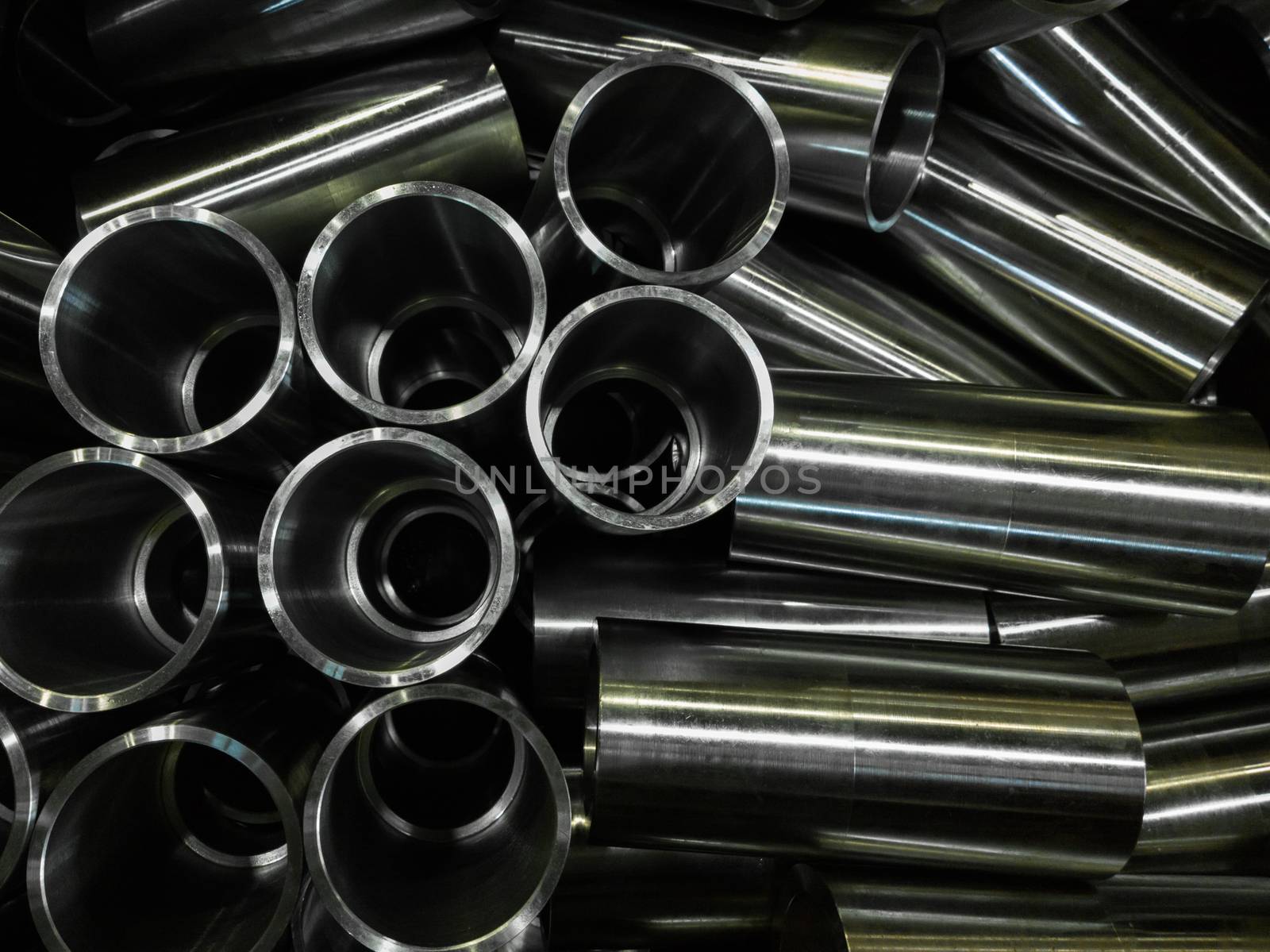 dark industrial background with cnc machined shiny steel pipes - selective focus and lens blur technique