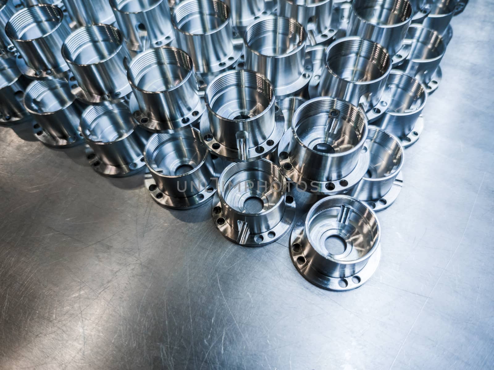 Shiny metal parts after cnc turning, drilling and machining on steel surface with selective focus for industrial background.