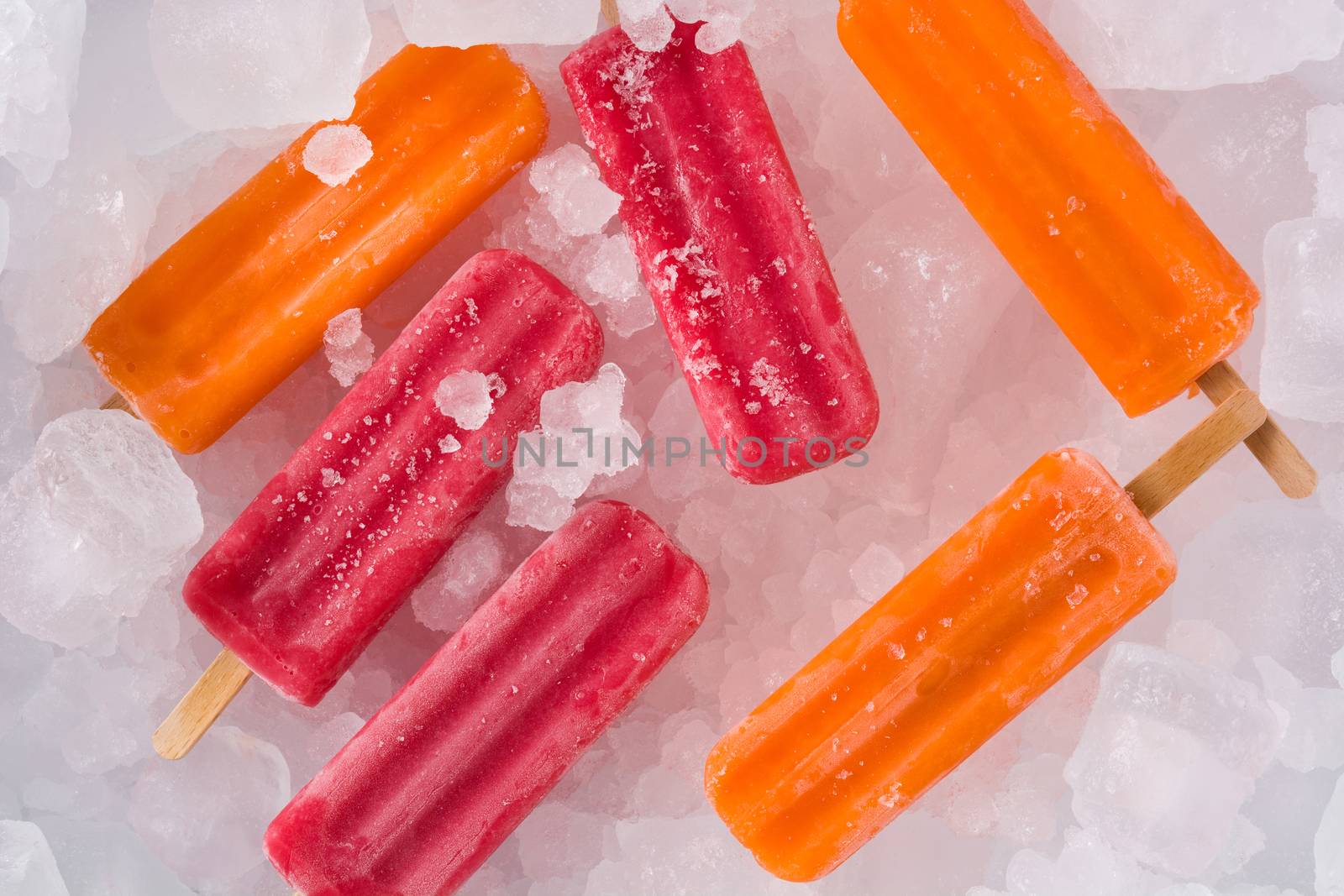 Orange and strawberry popsicles on ice cubes. Top view. Copyspace by chandlervid85