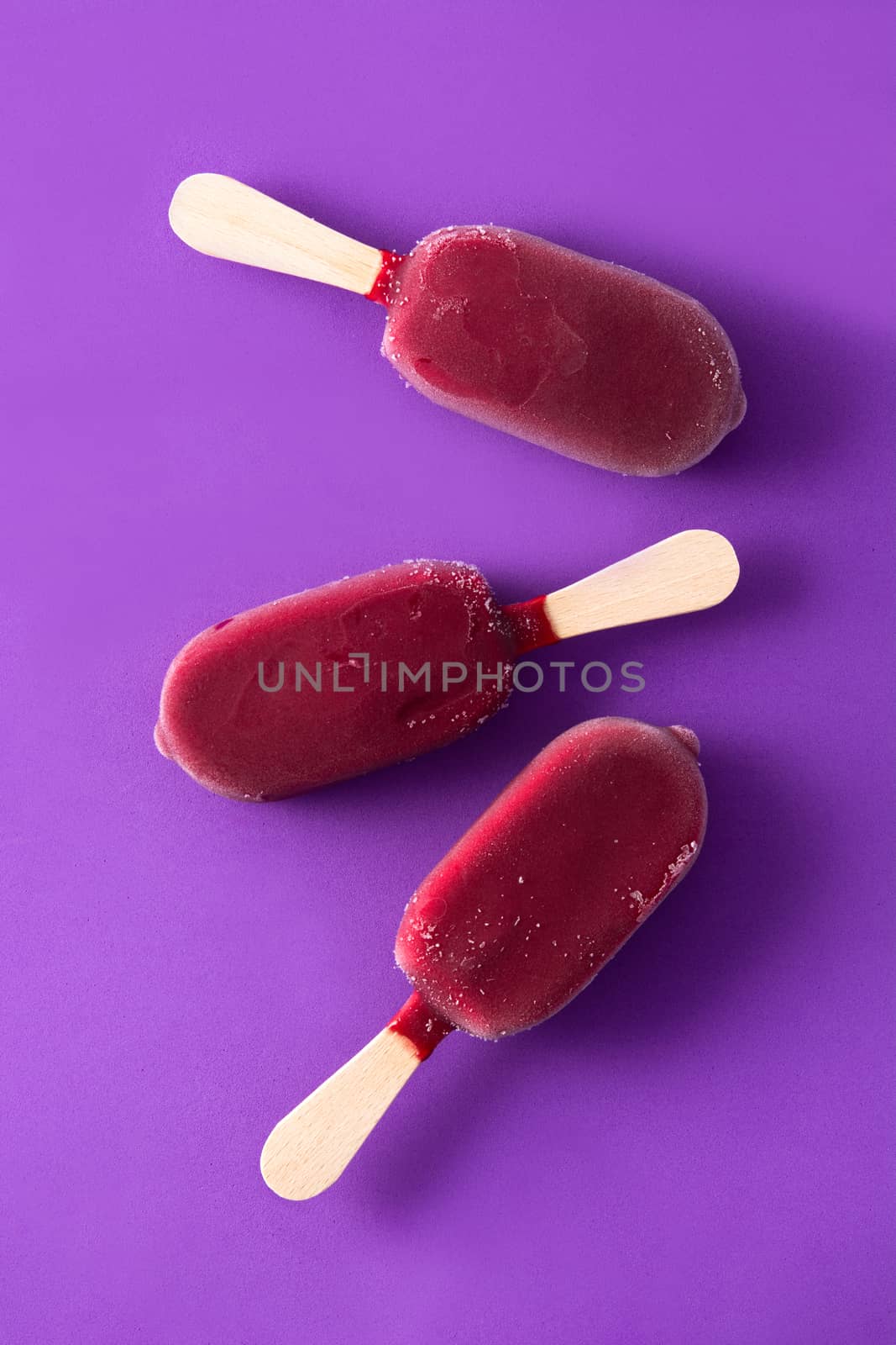 Strawberry popsicle on violet background.