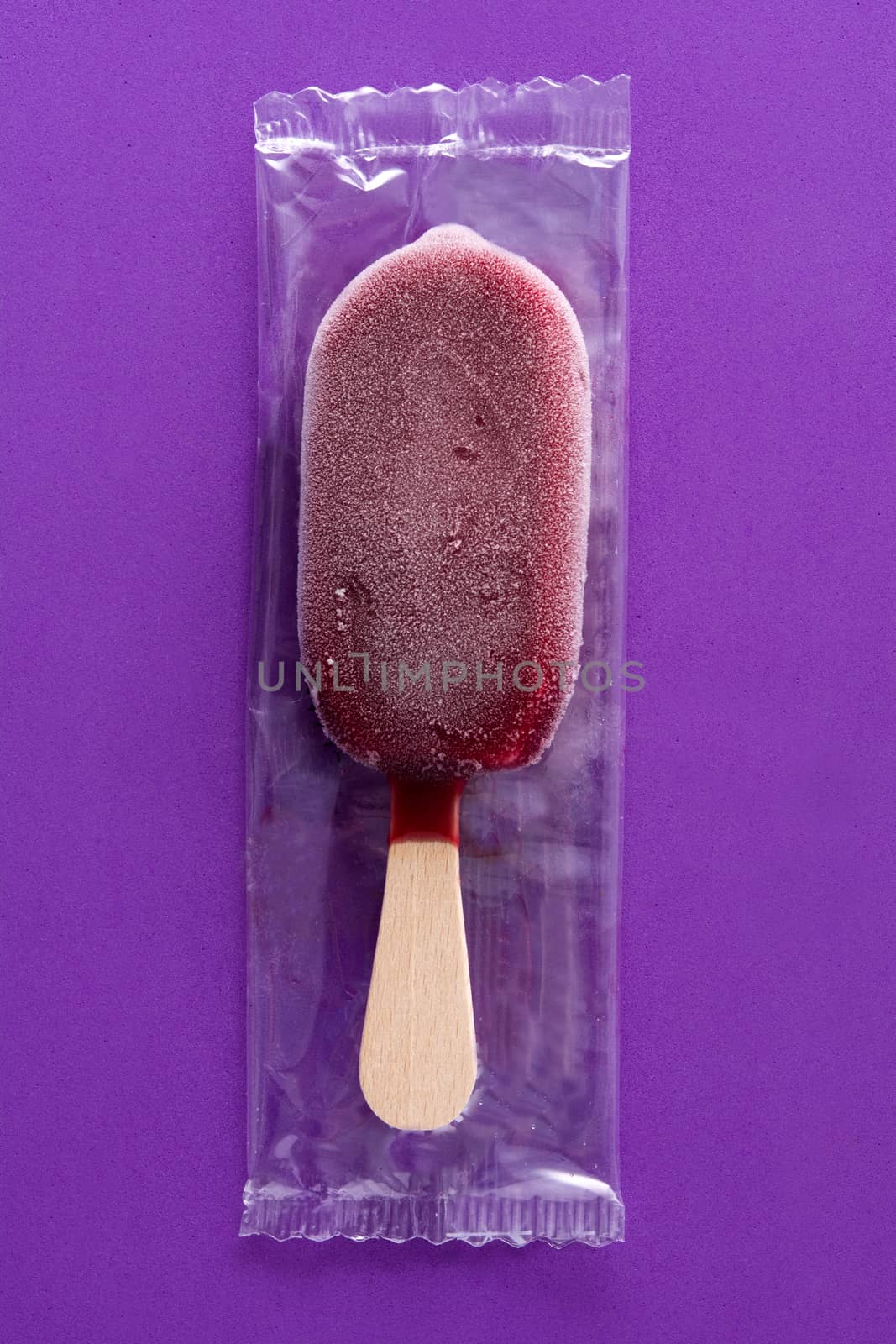 Packed strawberry popsicle on violet background.