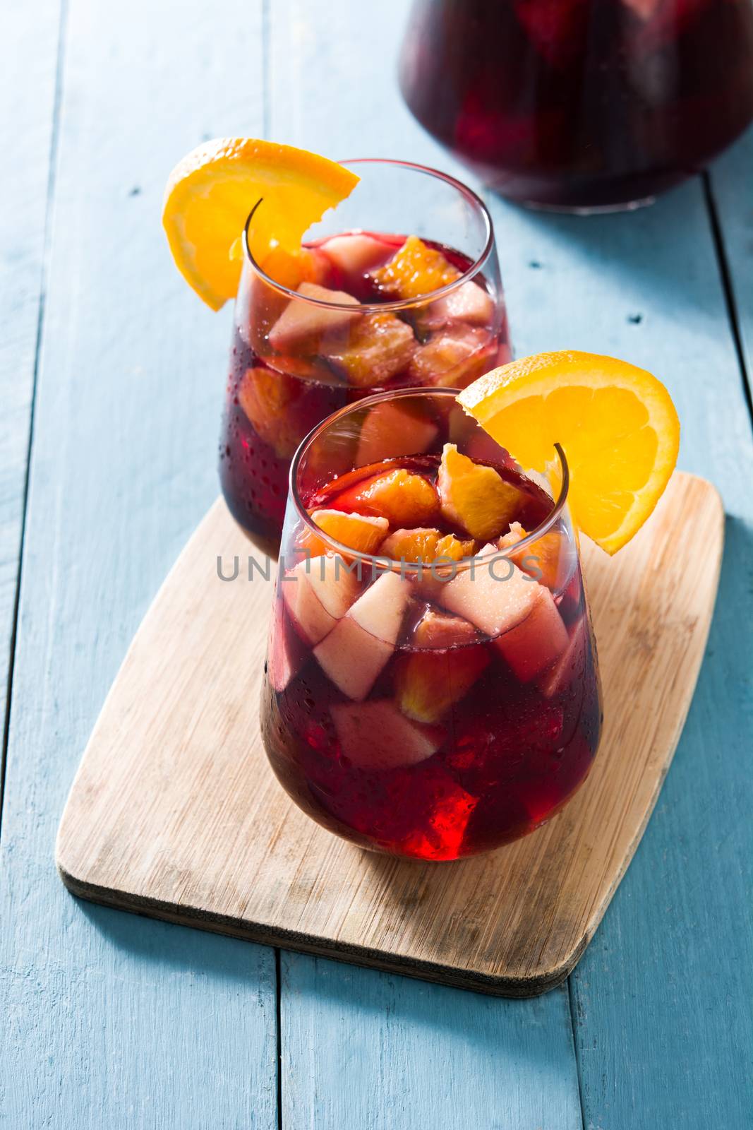 Red wine sangria in glass on blue wooden table.