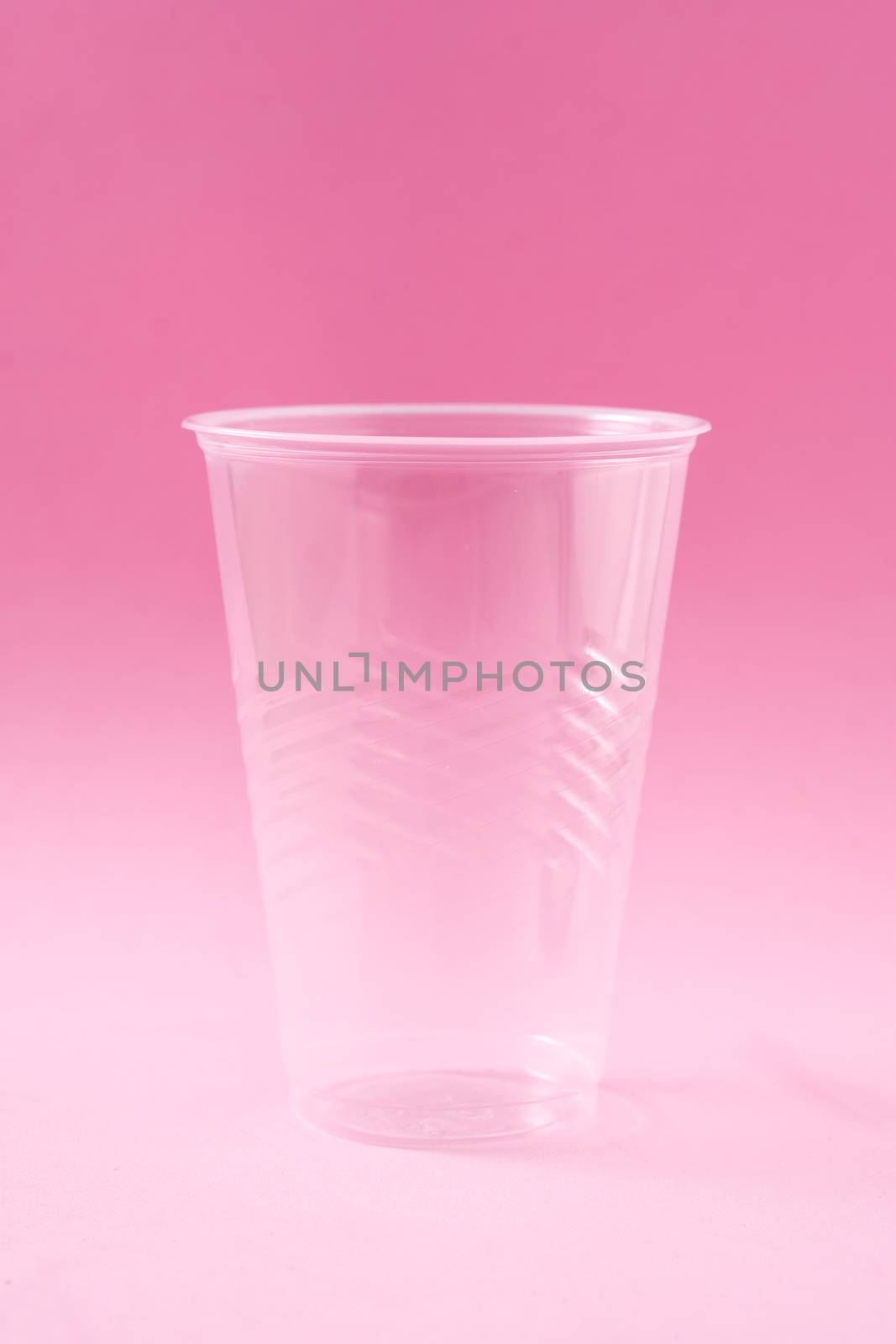 Disposable waste plastic cups on pink background