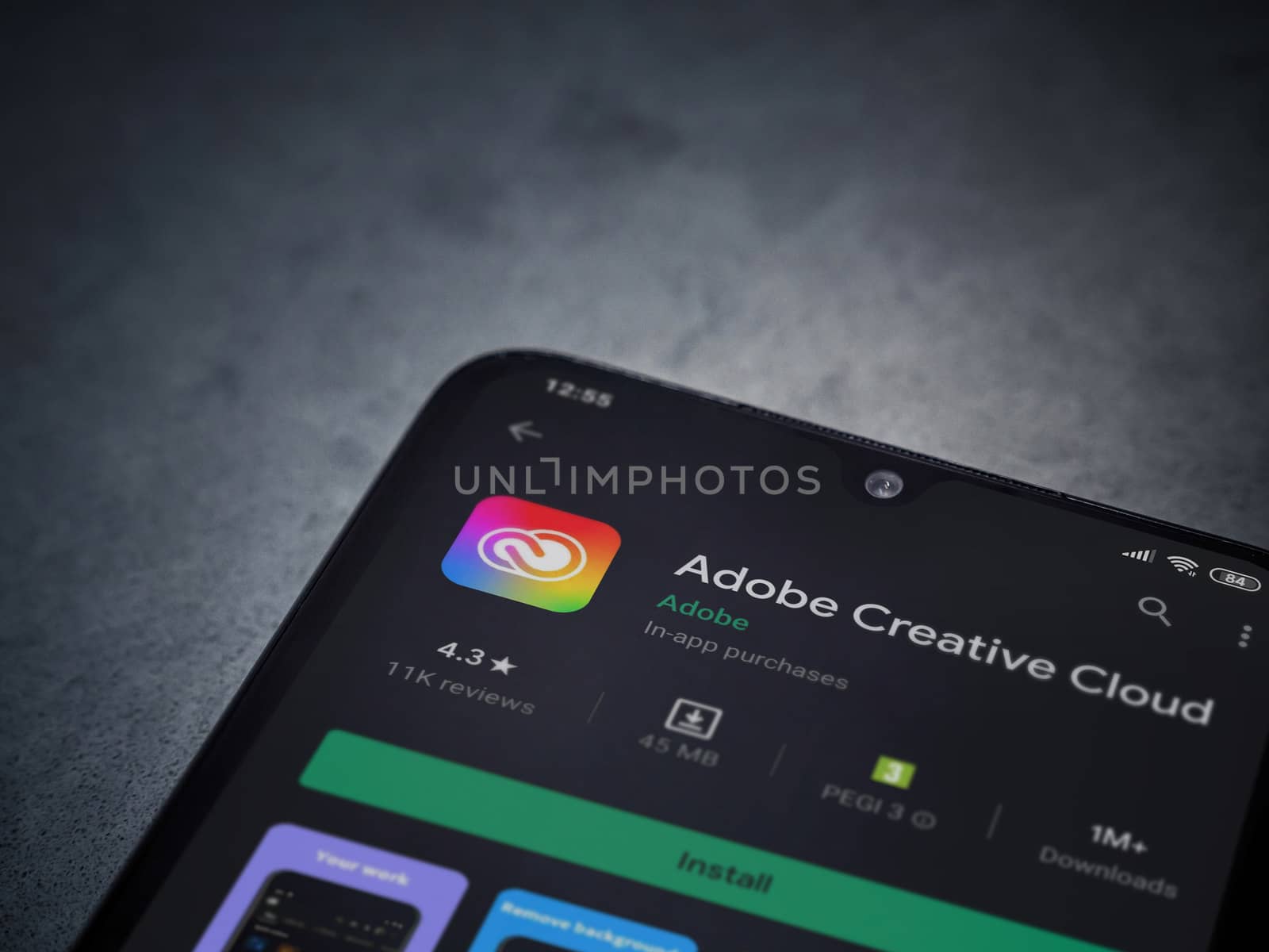Lod, Israel - July 8, 2020: Adobe Creative Cloud app play store page on the display of a black mobile smartphone on a dark marble stone background. Top view flat lay with copy space.