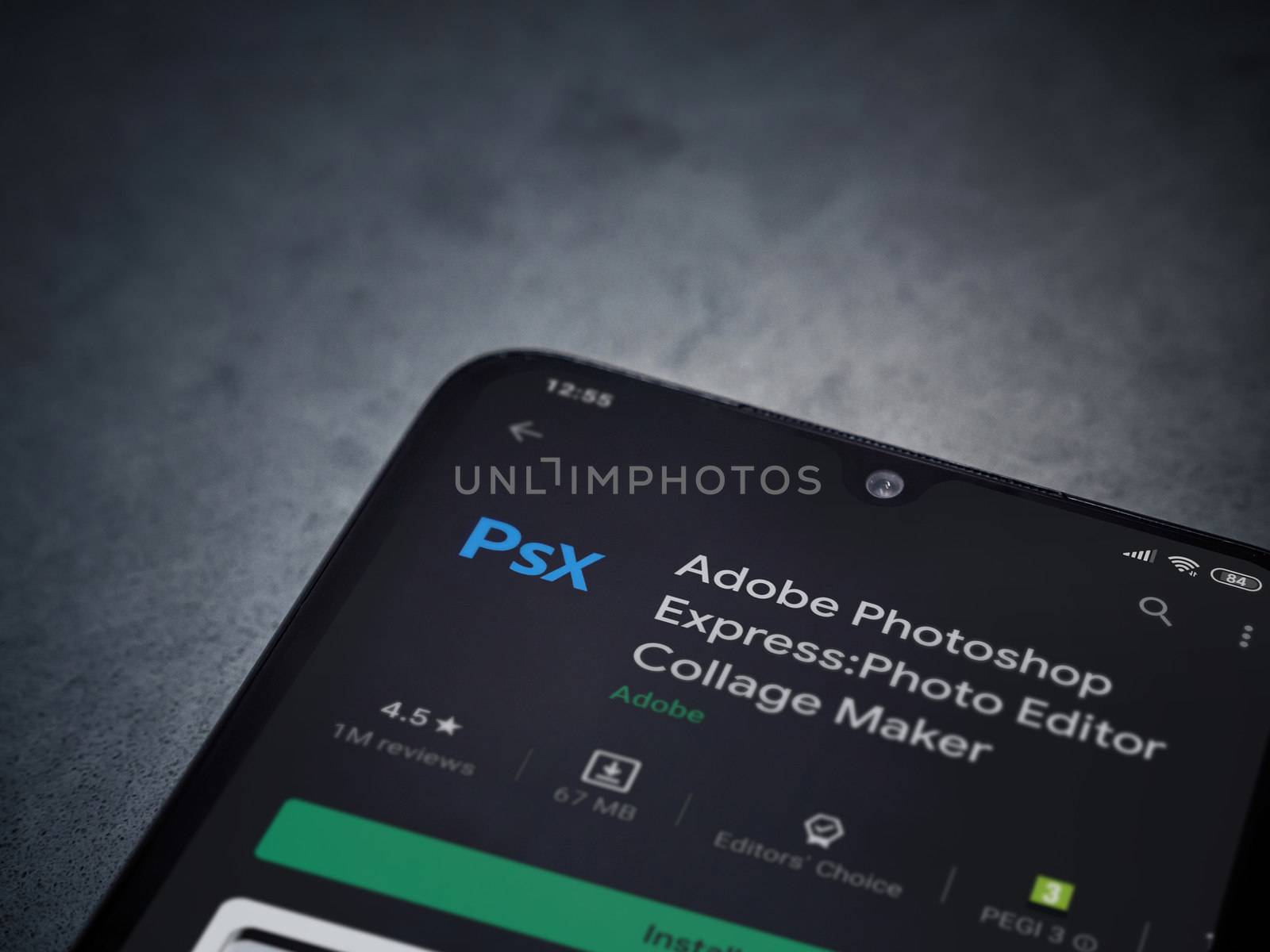 Lod, Israel - July 8, 2020: Adobe Photoshop Express Photo Editor app play store page on the display of a black mobile smartphone on a dark marble stone background. Top view flat lay with copy space.