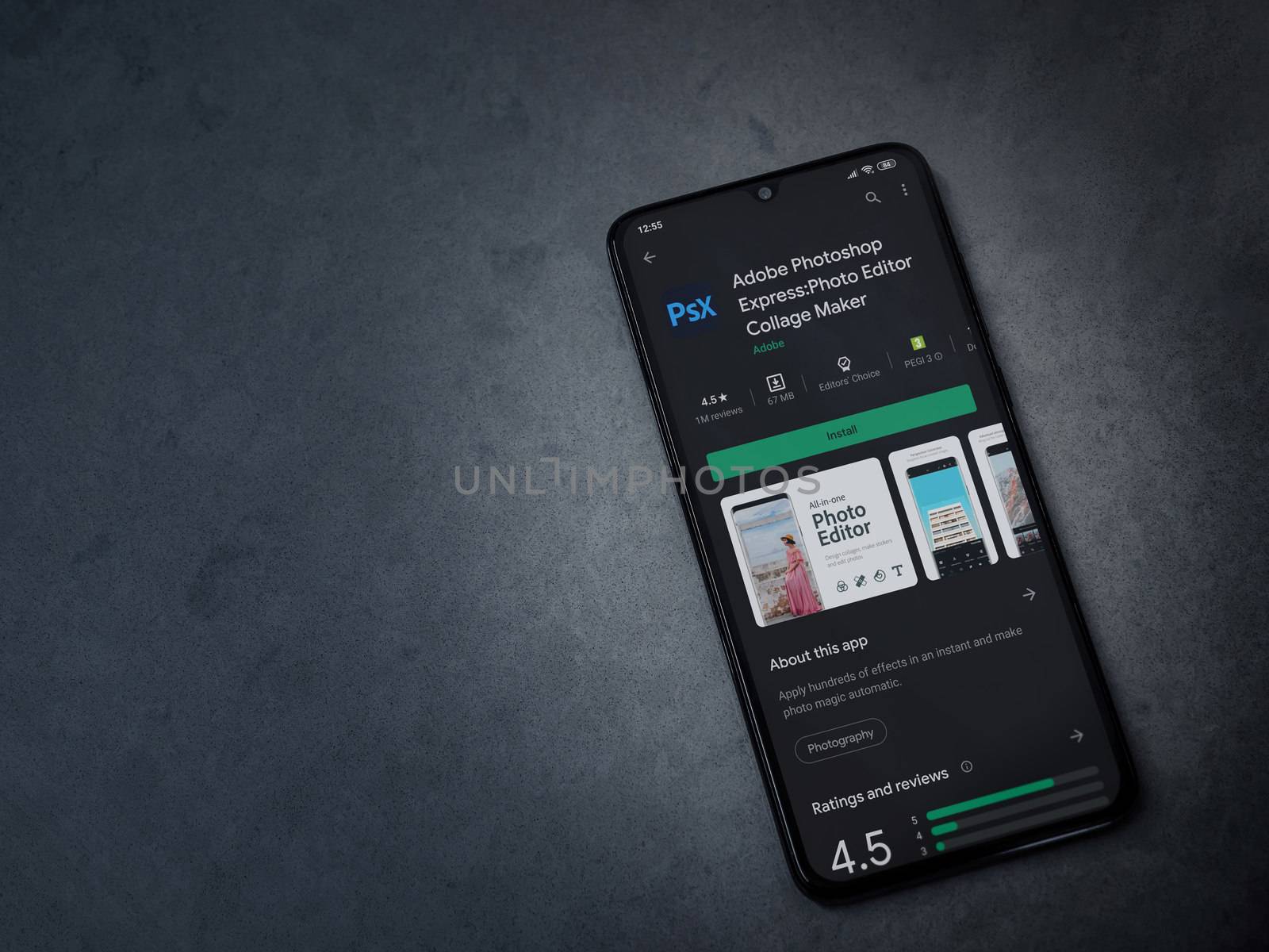 Lod, Israel - July 8, 2020: Adobe Photoshop Express Photo Editor app play store page on the display of a black mobile smartphone on a dark marble stone background. Top view flat lay with copy space.