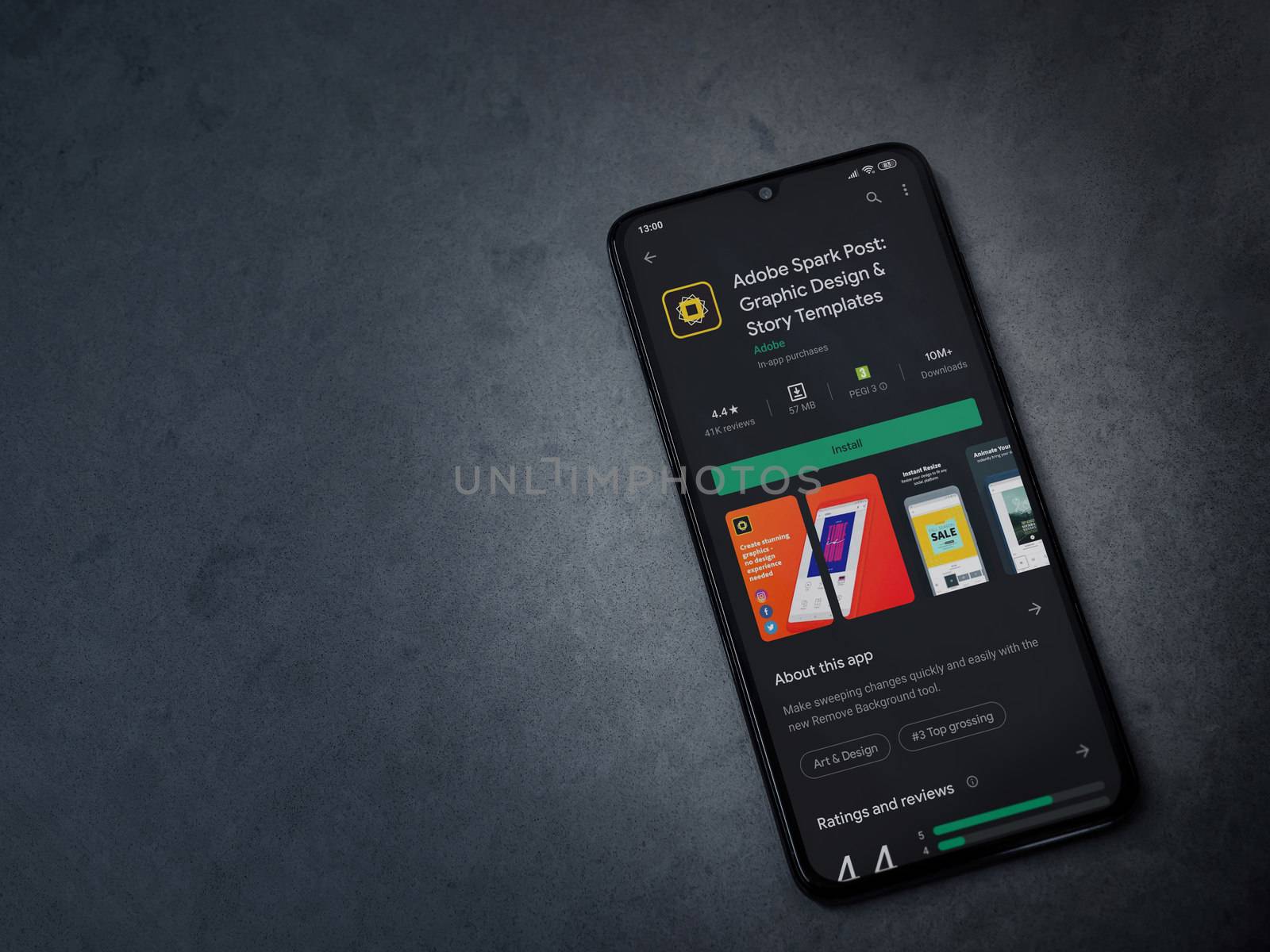 Lod, Israel - July 8, 2020: Adobe Spark Post - Graphic Design and Story Templates app play store page on the display of a black mobile smartphone on a dark marble stone background.Top view flat lay with copy space