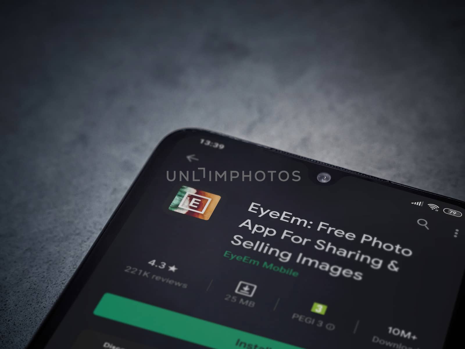 Lod, Israel - July 8, 2020: EyeEm - Sharing and Selling Images app play store page on the display of a black mobile smartphone on a dark marble stone background. Top view flat lay with copy space.
