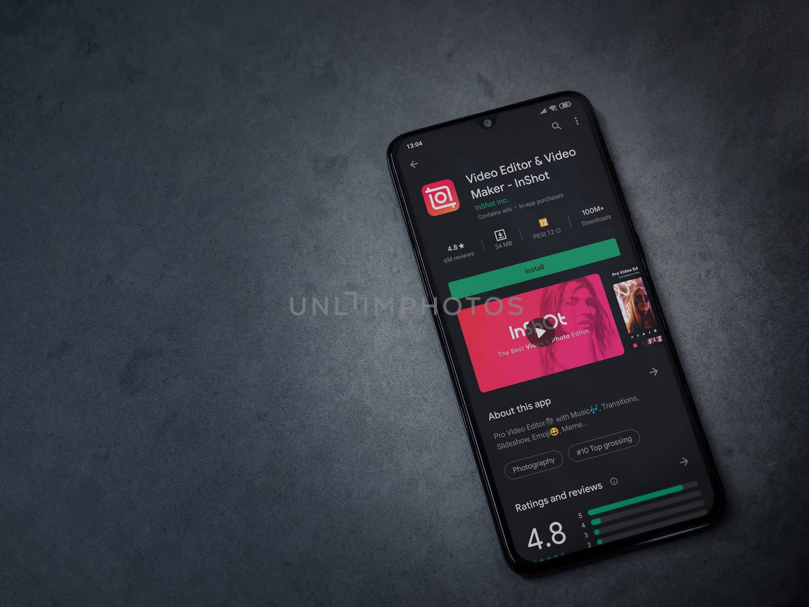 Lod, Israel - July 8, 2020: InShot - Video Editor and Movie Maker app play store page on the display of a black mobile smartphone on a dark marble stone background. Top view flat lay with copy space.