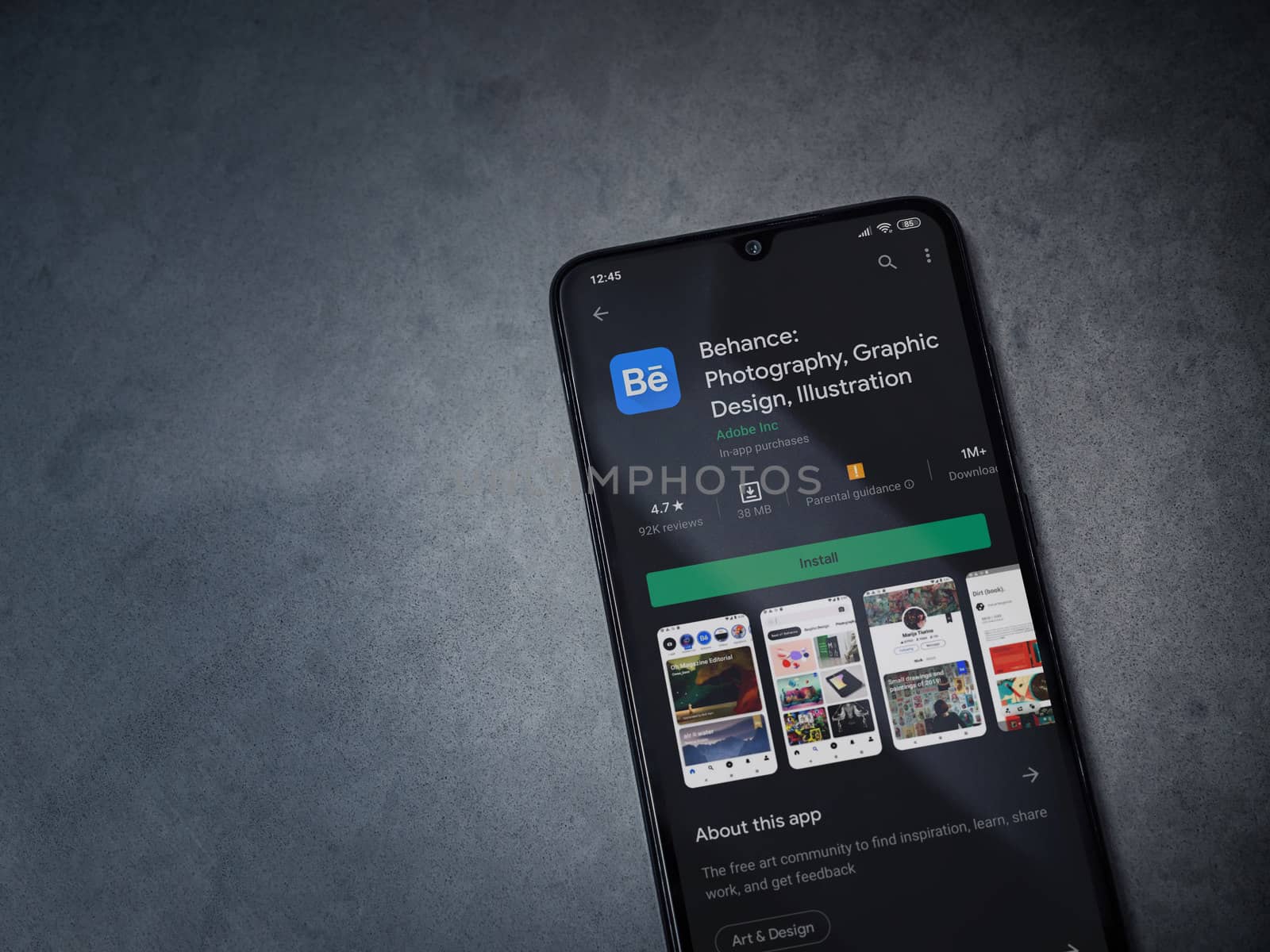 Lod, Israel - July 8, 2020: Adobe Behance app play store page on the display of a black mobile smartphone on a dark marble stone background. Top view flat lay with copy space. 