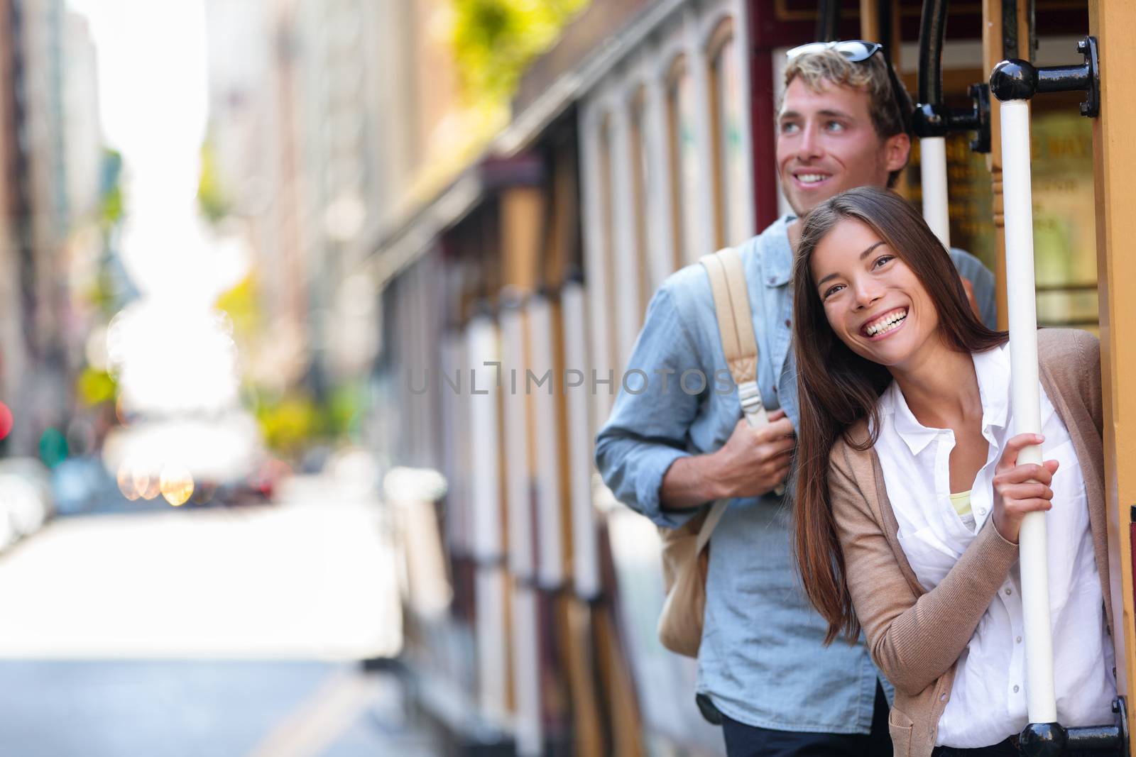 San Francisco city tourists riding cable car tramway tourism people lifestyle. Young interracial couple enjoying ride of cable car railway system, popular travel attraction.