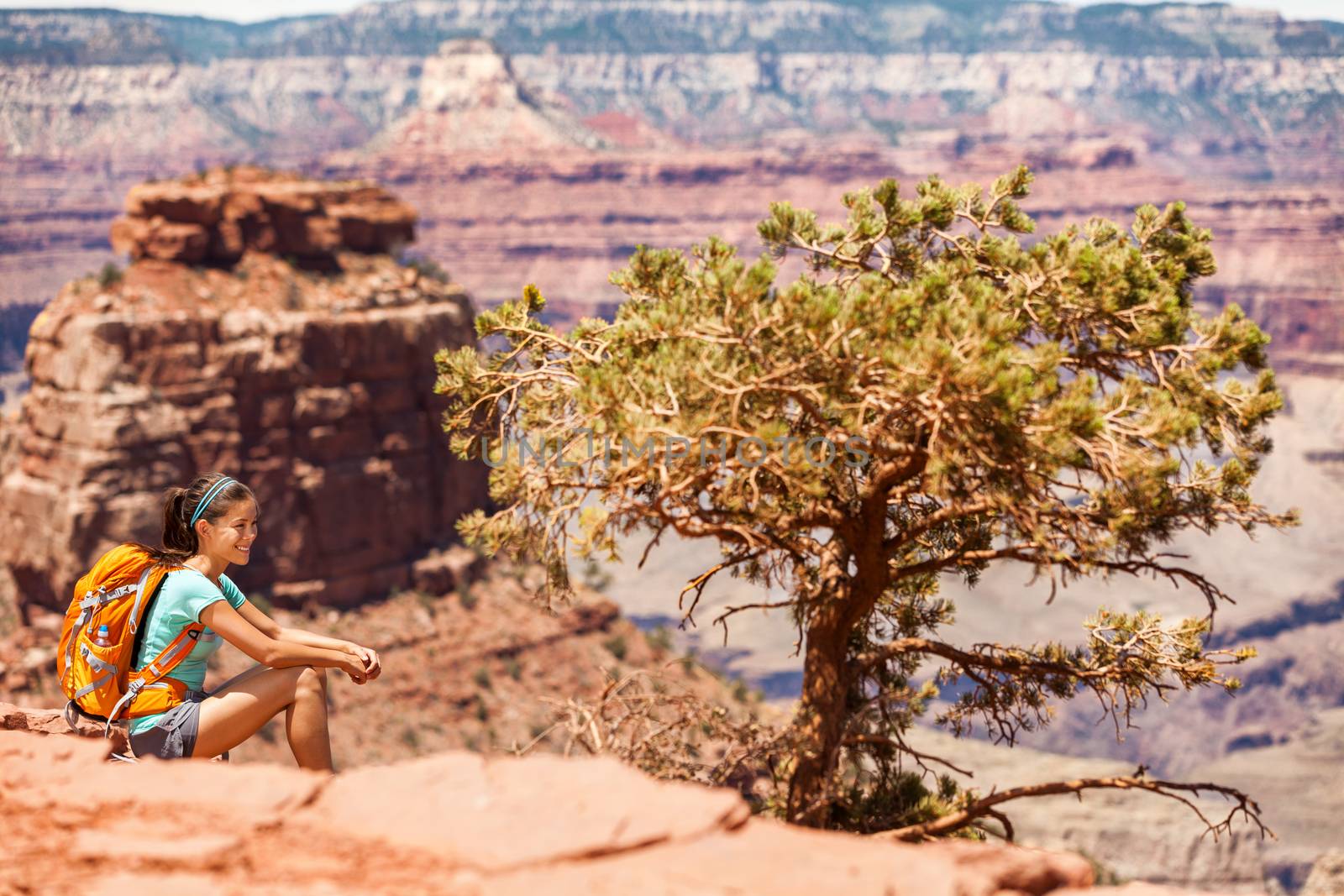 Girl hiker hiking on landscape trail in Grand Canyon National Park, USA. Adventure backpacker with bag sitting enjoying view of nature.