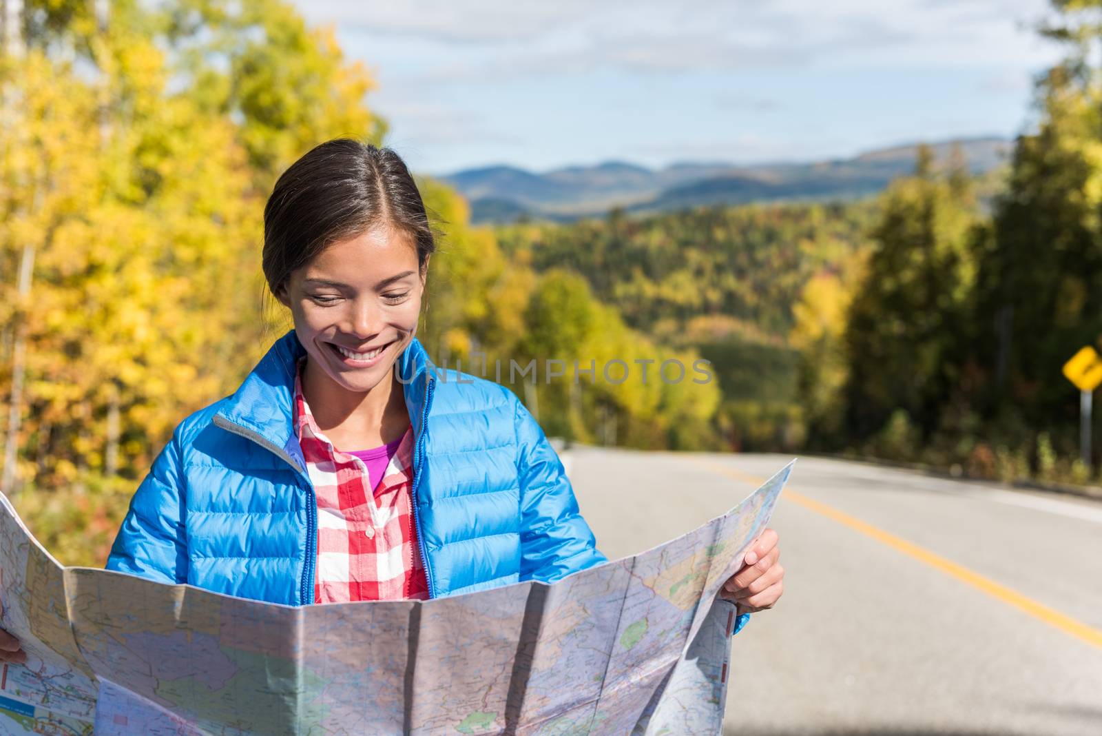 asian woman looking at map directions on road trip by Maridav