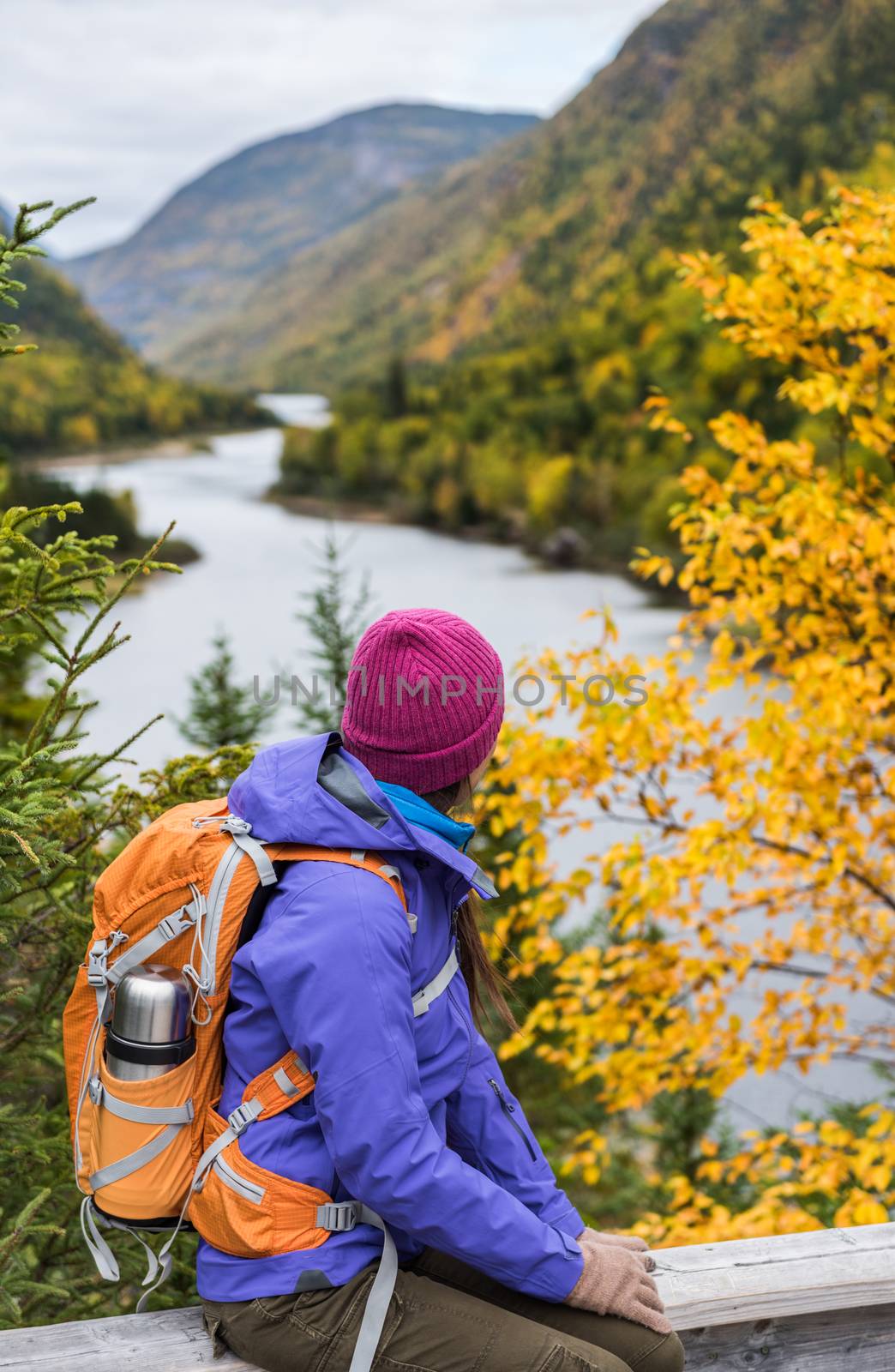 Woman hiker hiking looking at scenic view of fall foliage mountain landscape . Adventure travel outdoors person standing relaxing near river during nature hike in autumn season.