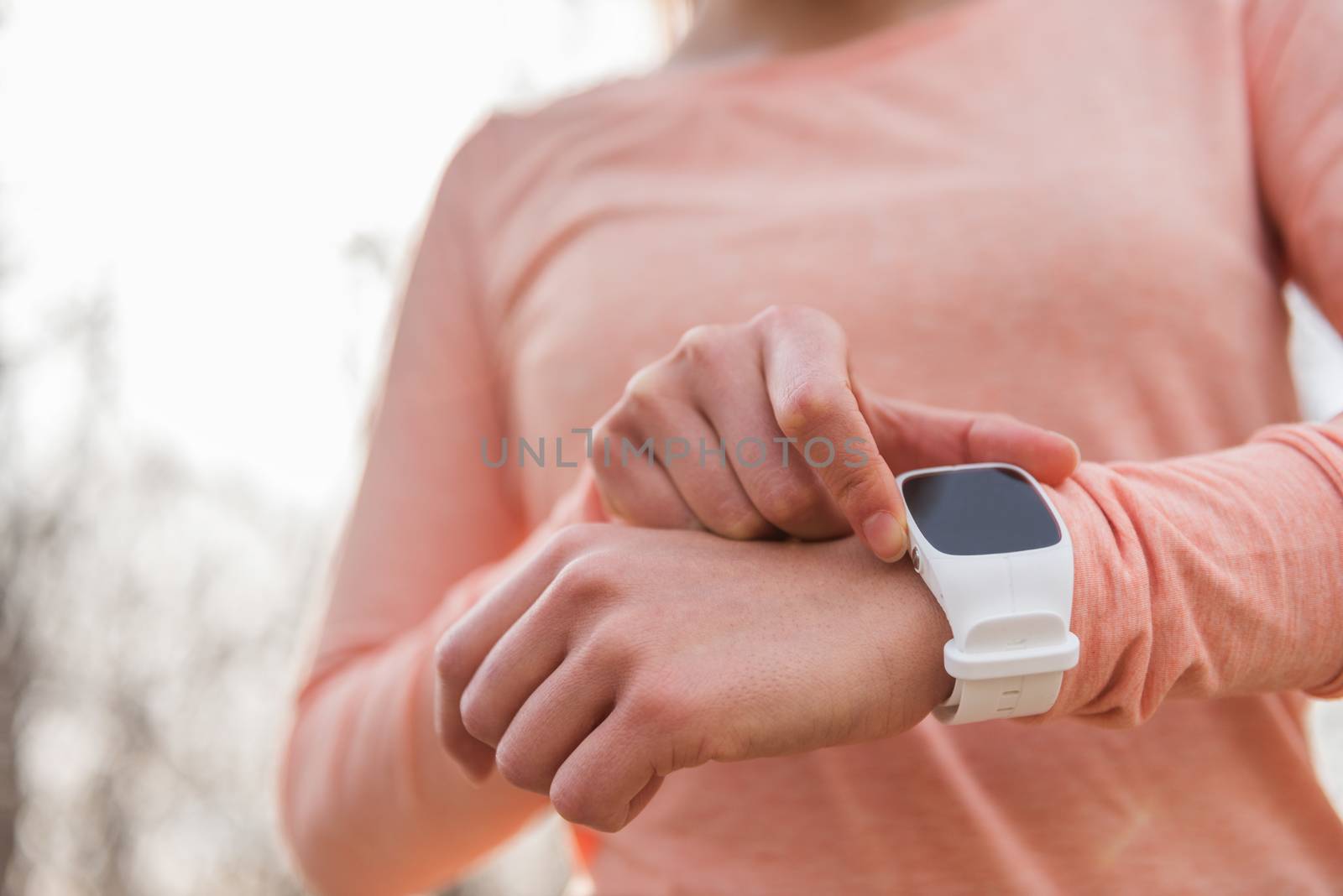 Active woman getting ready setting smartwatch as fitness monitor. smart watch running athlete preparing for cardio workout run race. Sportswoman checking device in cold weather autumn, spring or fall. by Maridav