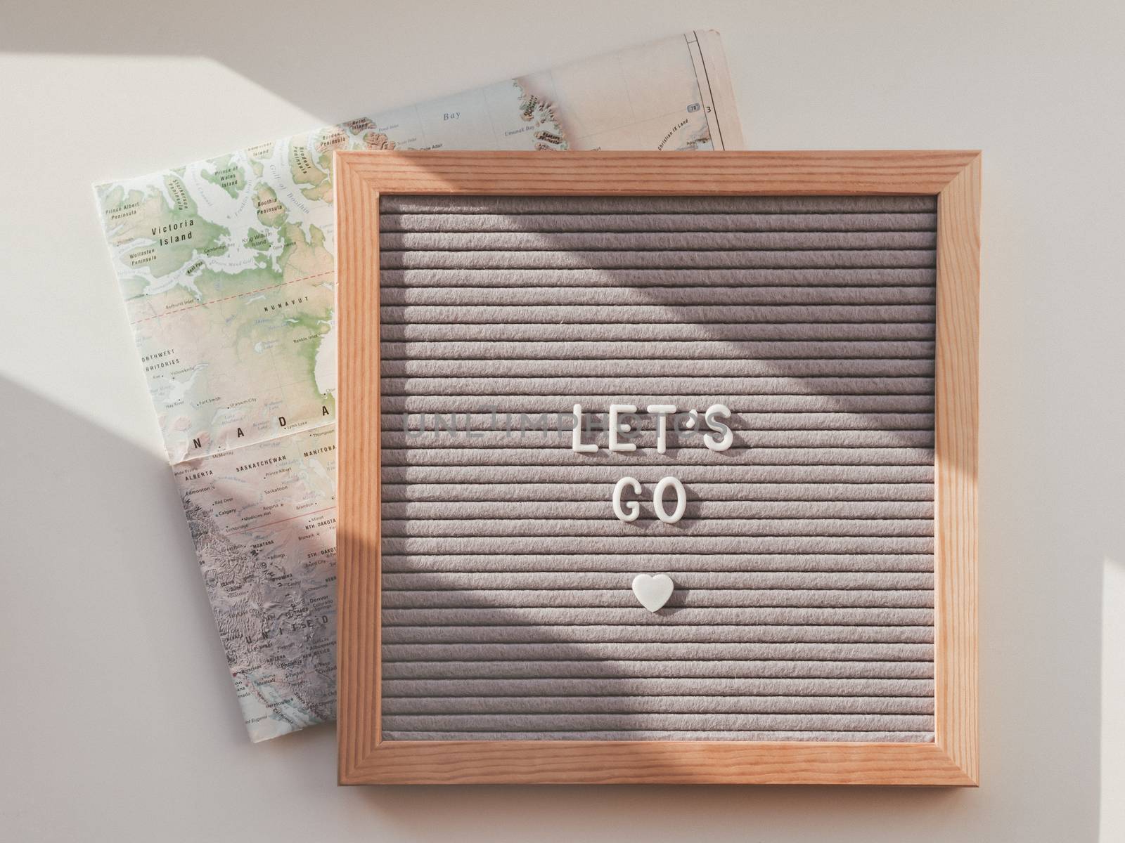 Letter board with words LET'S GO and touristic map of USA. Top view on flat lay board with heart, symbol of love to travel. Wanderlust background with sunlight and shadow.