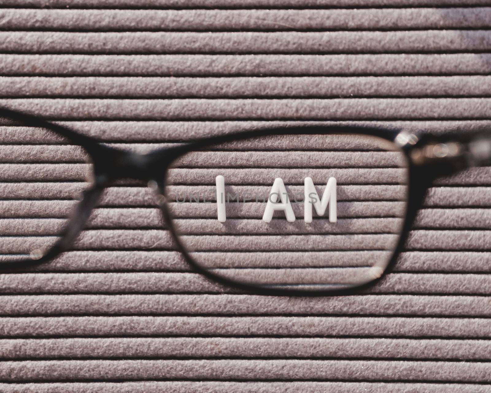 Top view on letterboard with words I AM through eyeglasses. Flat lay concept of psychological self-regulation or gender identity. Social psychological issue. Closer look on psychological problems.