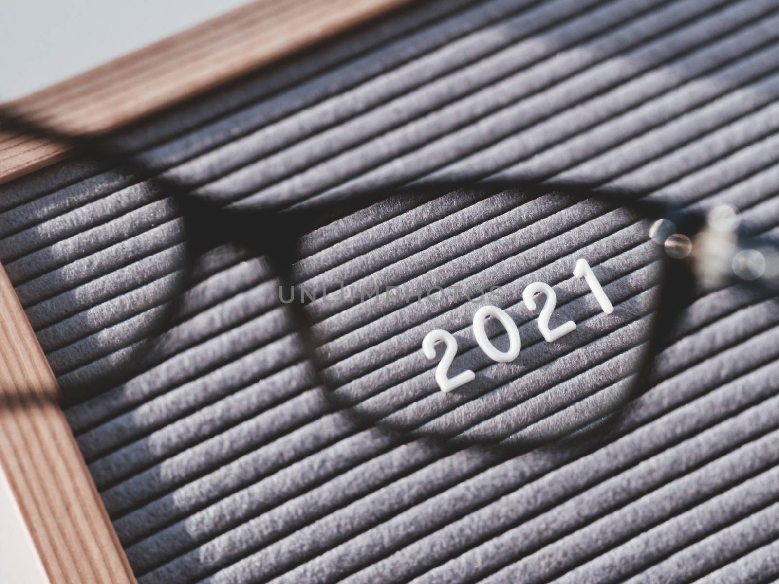 Top view on letterboard with numbers 2021 through eyeglasses. Flat lay concept of 2021 year results. 2021 review. Social, political or economical issue. Closer look on problems and achievements.