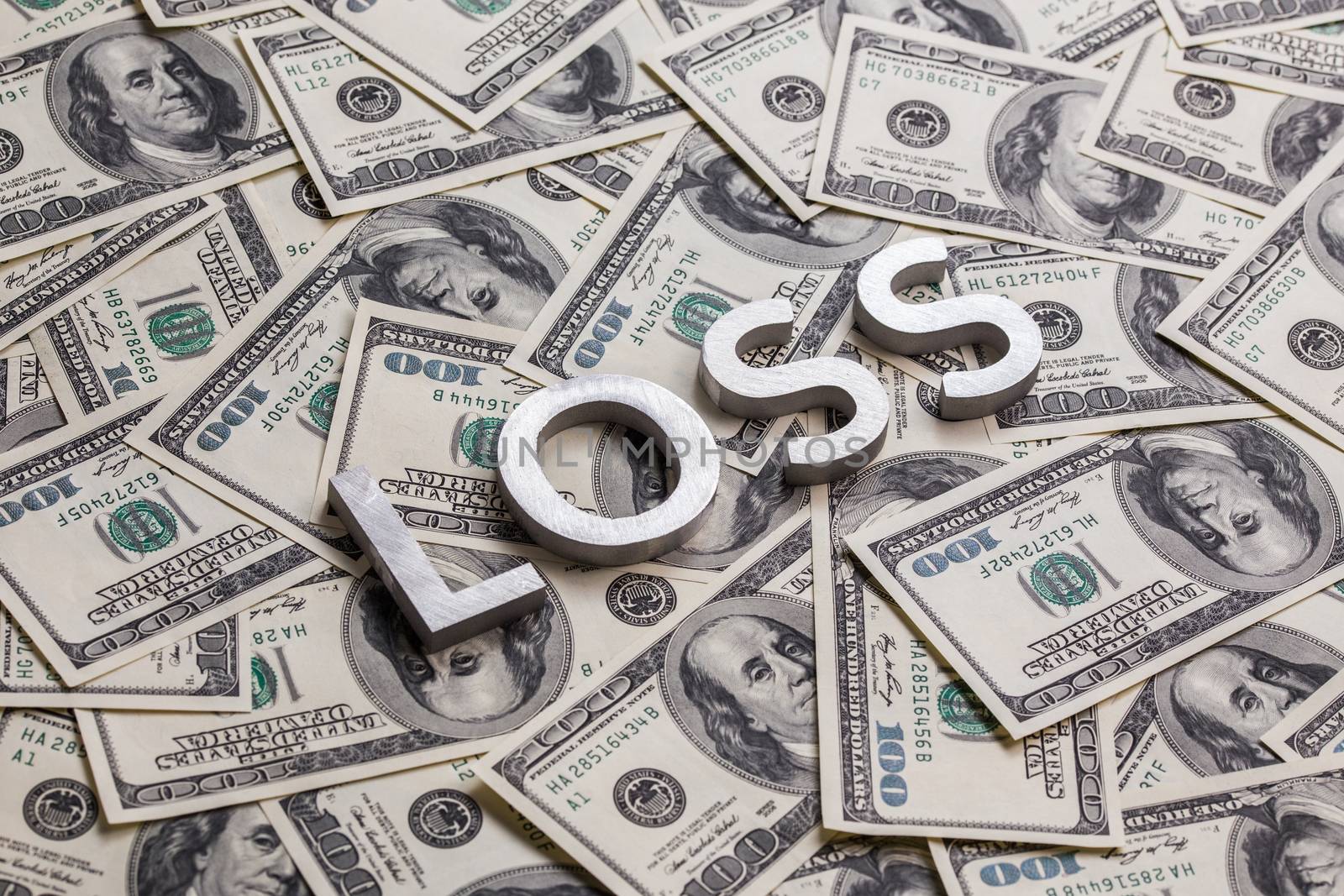 a word loss laid by metal letters on dollar banknotes background.