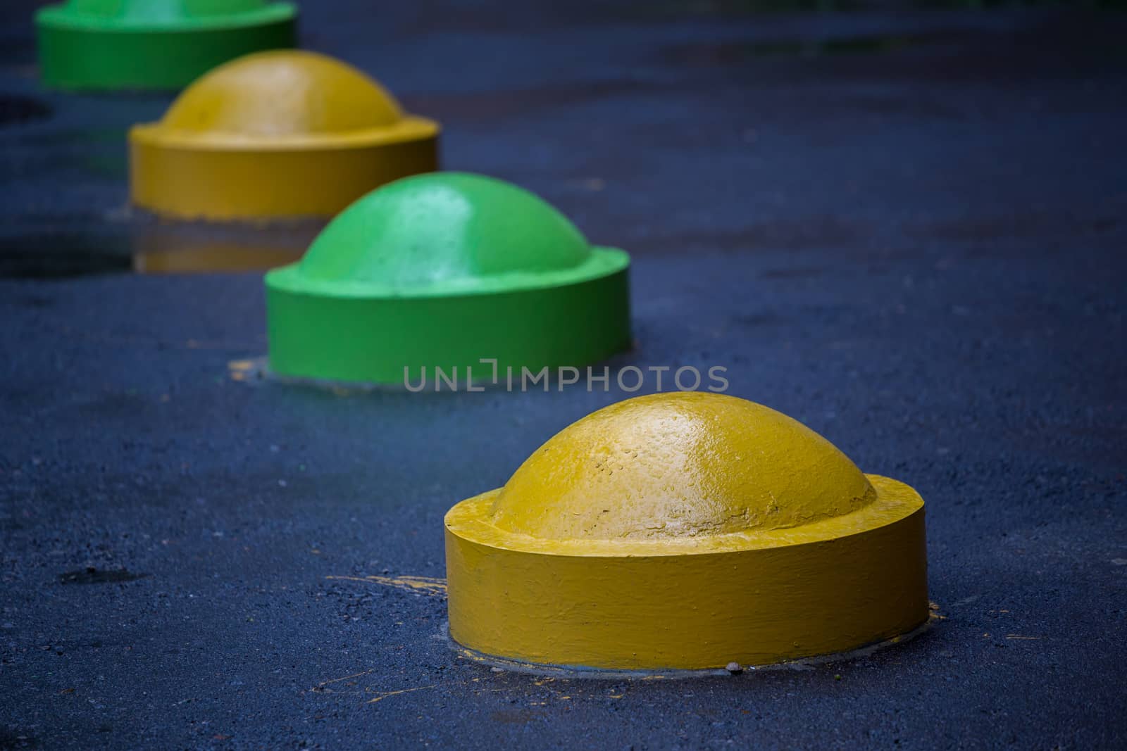 colorful concrete road parking prevention hemisphere bollards close-up with selective focus and blur.