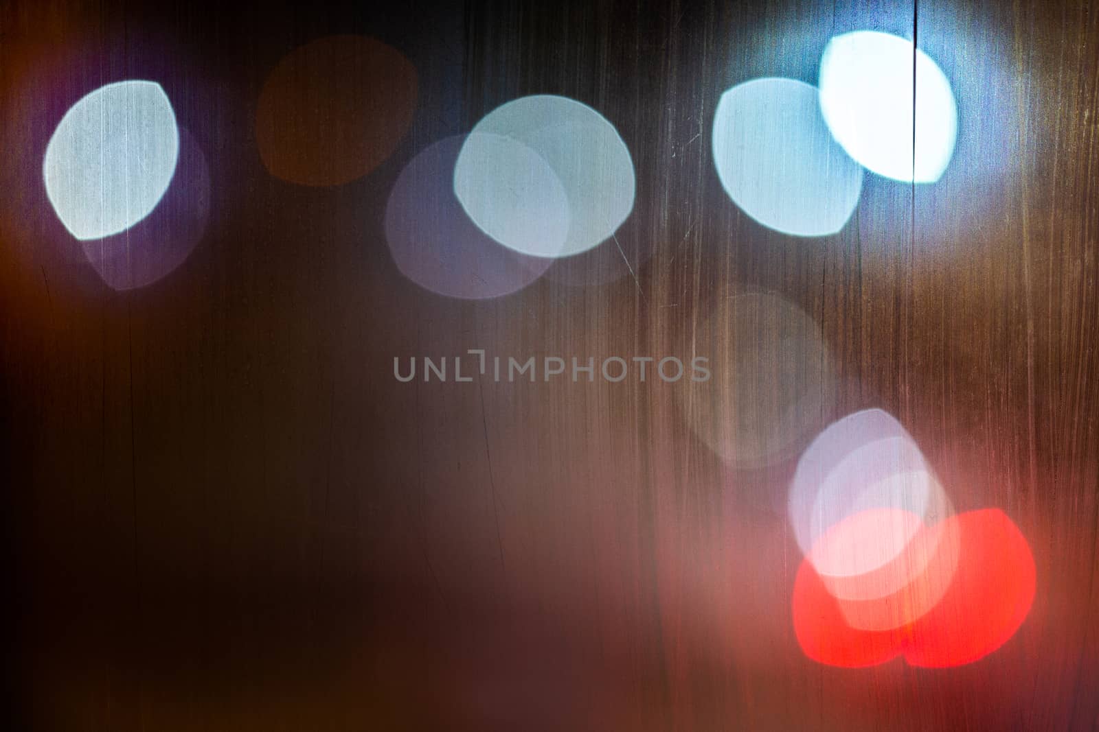 an abstract background night street lights bokeh through wet glass, close-up with selective focus.