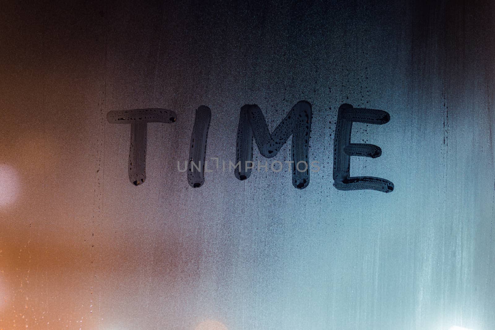 the word time handwritten by finger on night wet window glass.