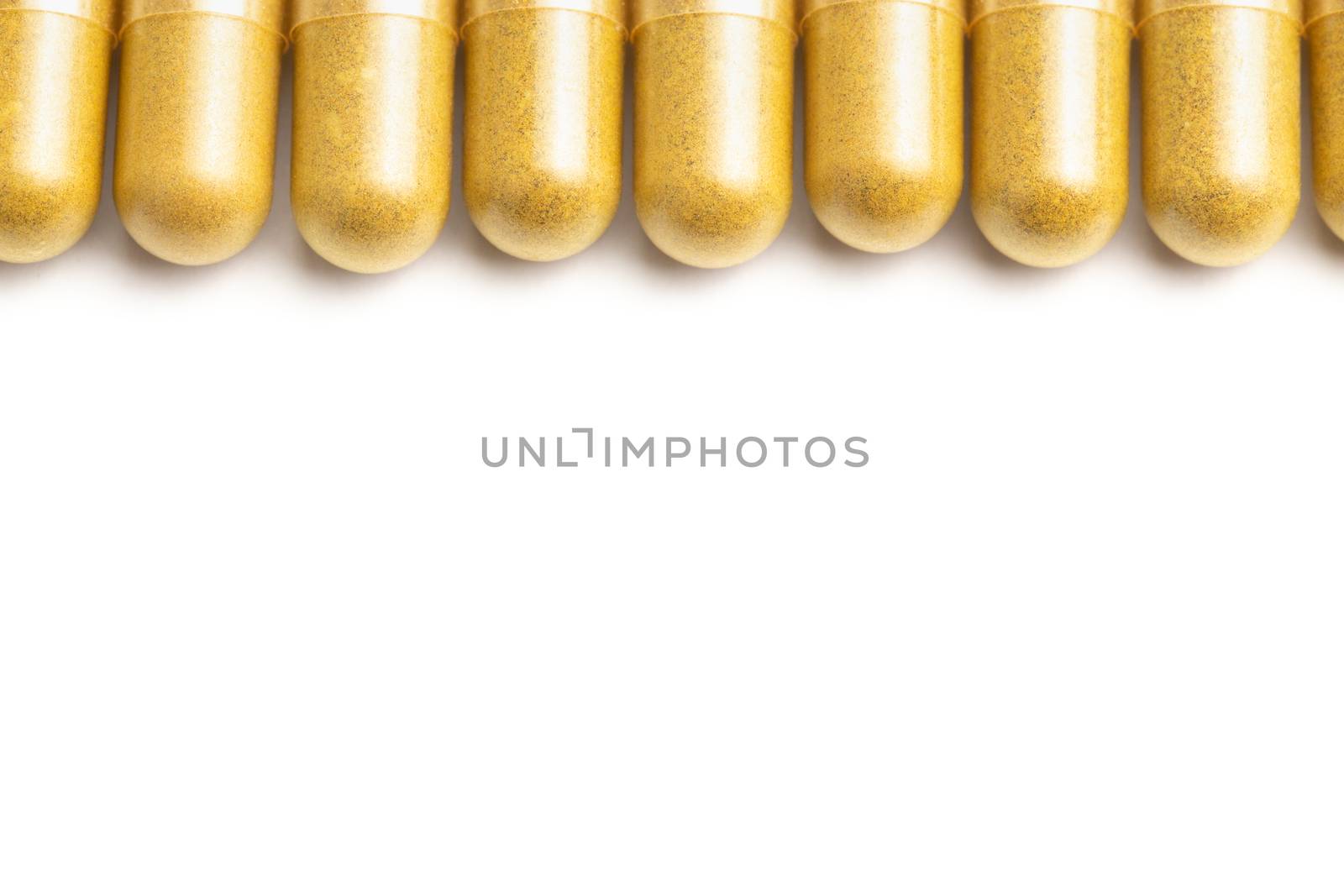 row of orange color organic capsules isolated on white background closeup with selective focus.