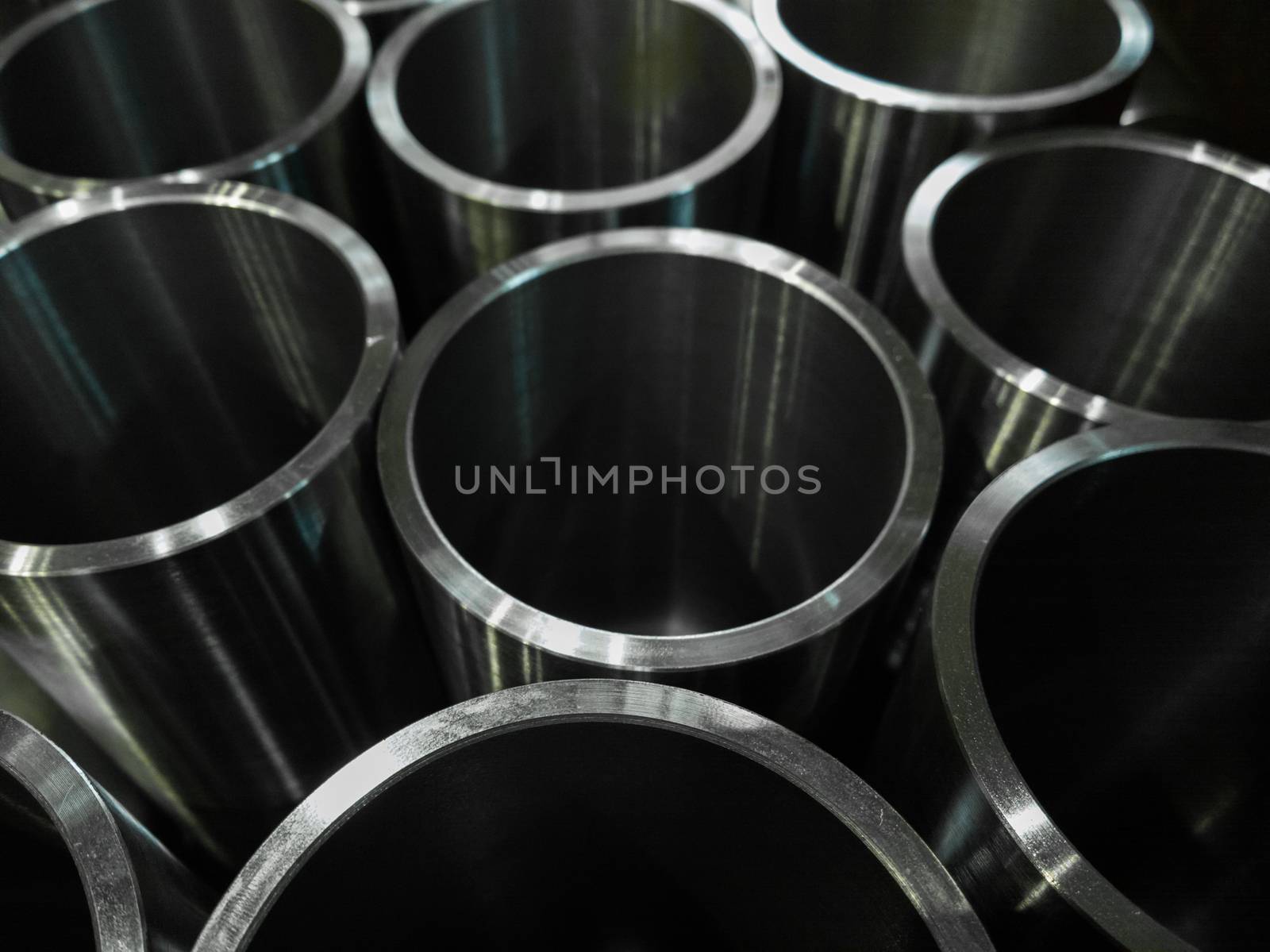 dark industrial background with cnc machined shiny steel pipes - selective focus and lens blur technique