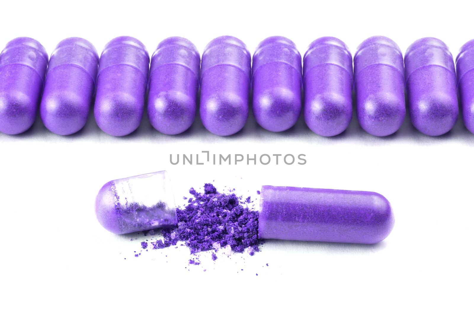 row of proton purple color organic capsules isolated on white background closeup with one opened.
