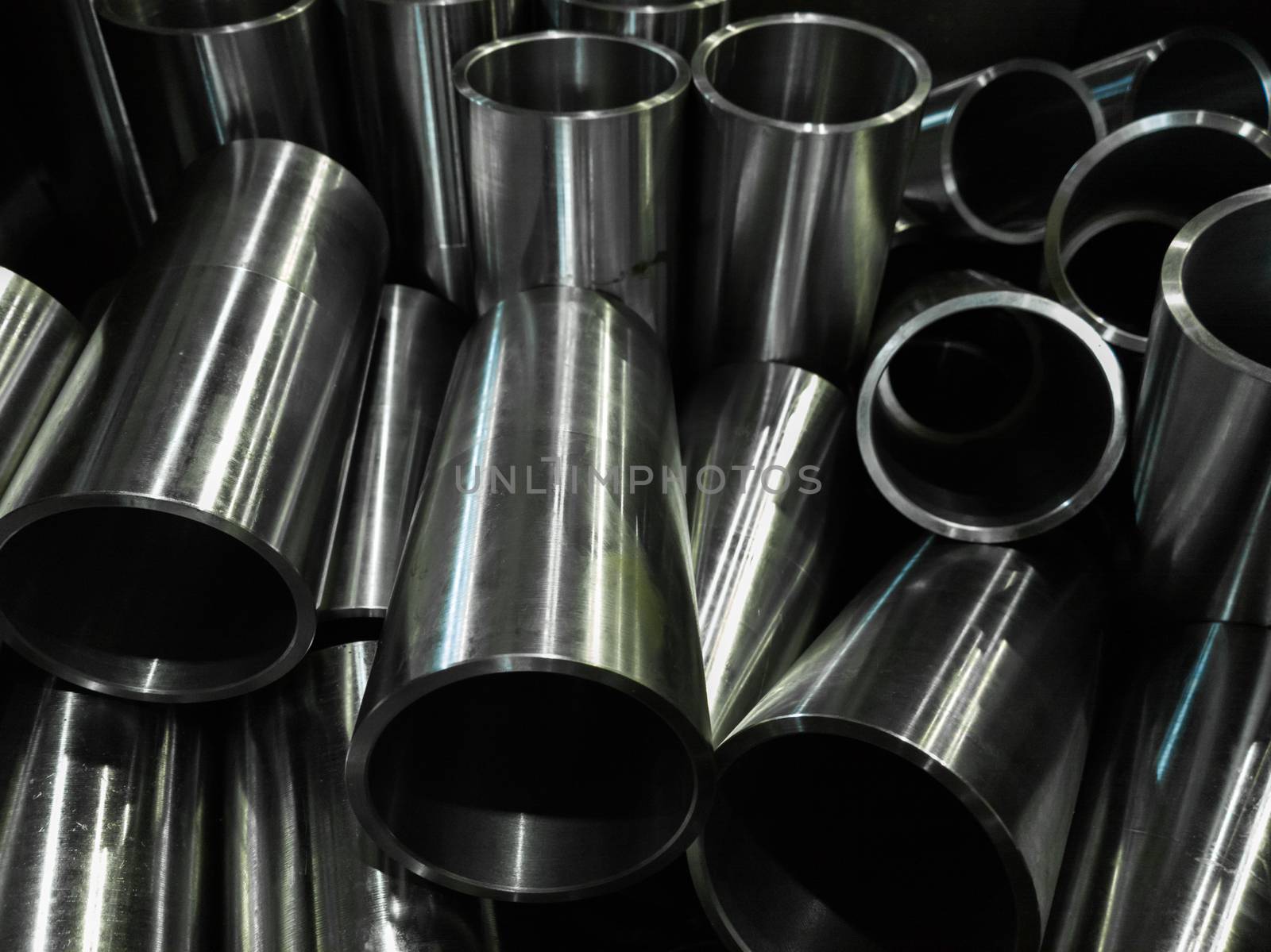 dark industrial background with cnc machined shiny steel pipes - selective focus and lens blur technique