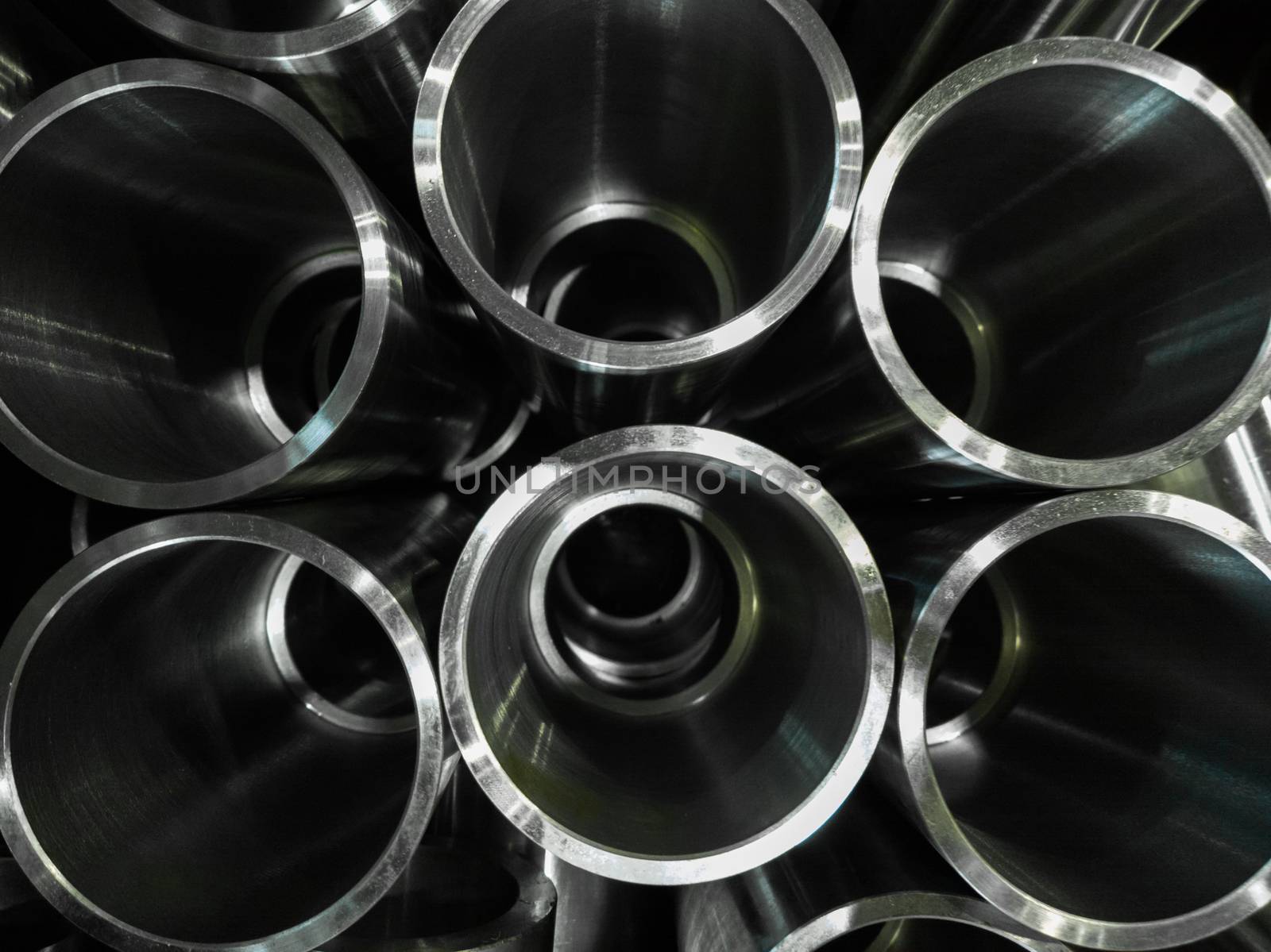 dark industrial background with cnc machined shiny steel pipes - selective focus and lens blur technique