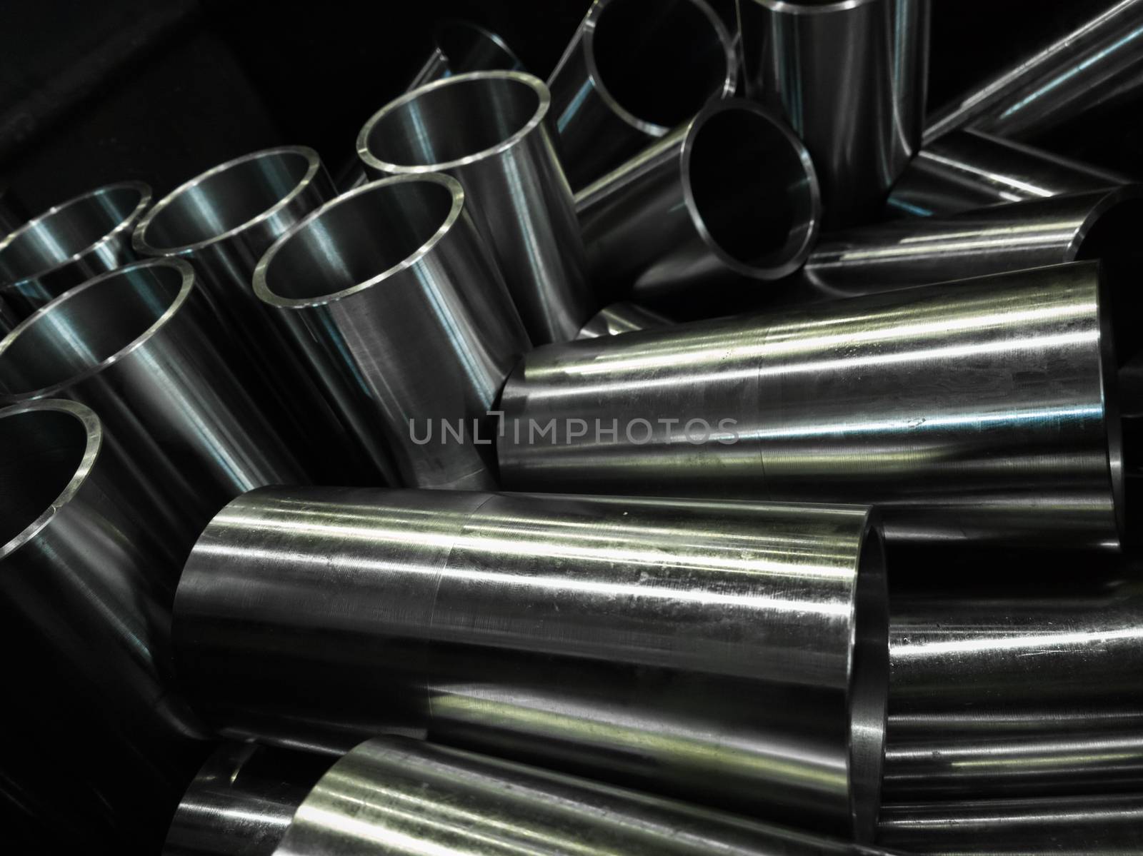 dark industrial background with cnc machined shiny steel pipes - selective focus and lens blur technique