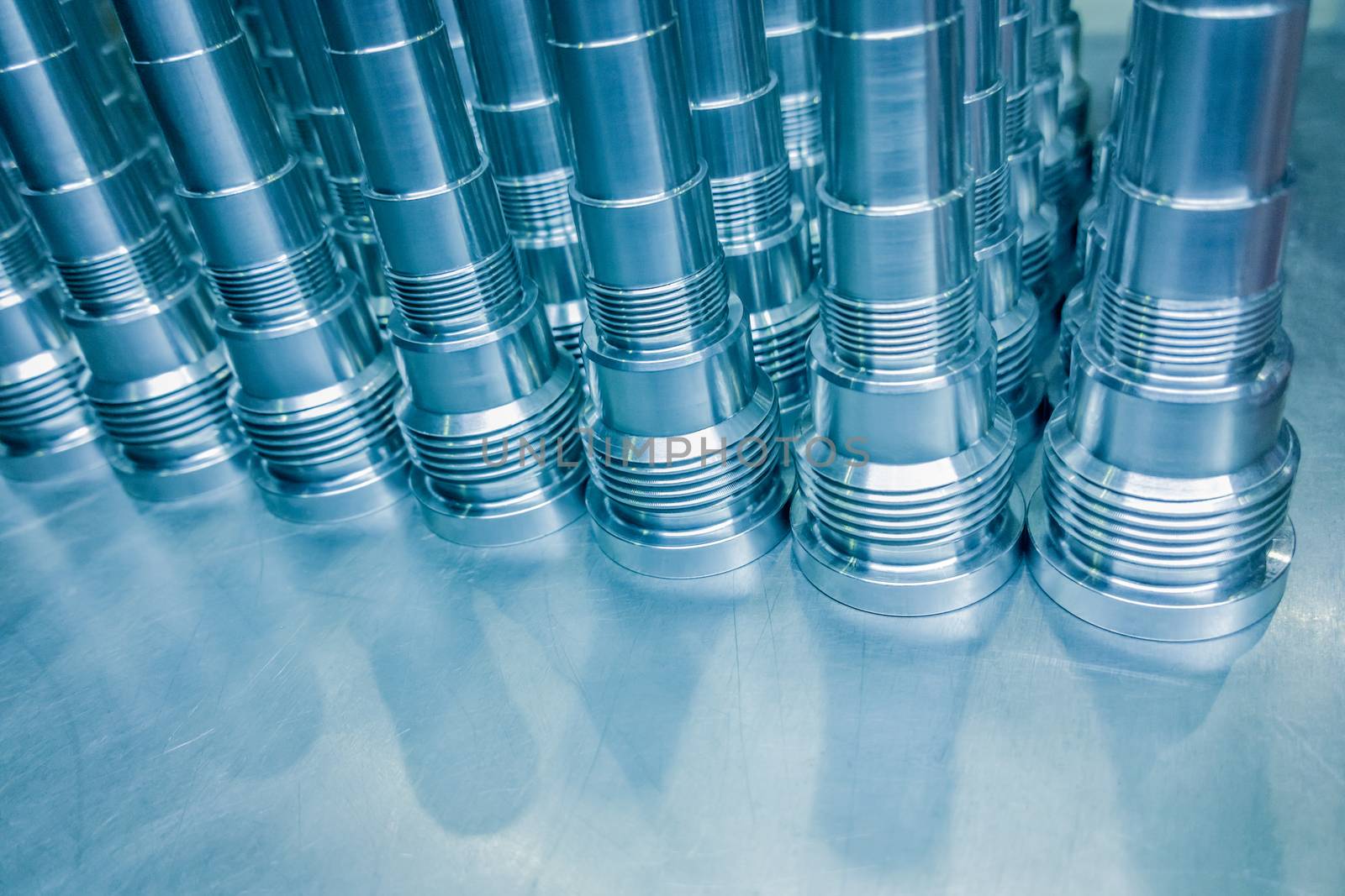 Shiny blue steel parts background, long clean steel threaded rods after fine cnc turning.
