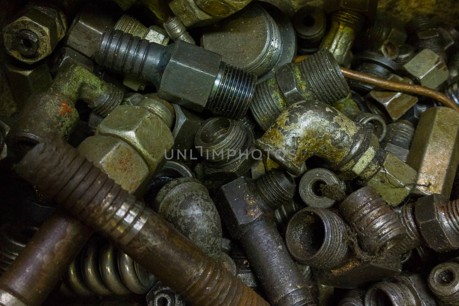 a pile of old dirty hydraulic fittings and tube parts closeup with selective focus.