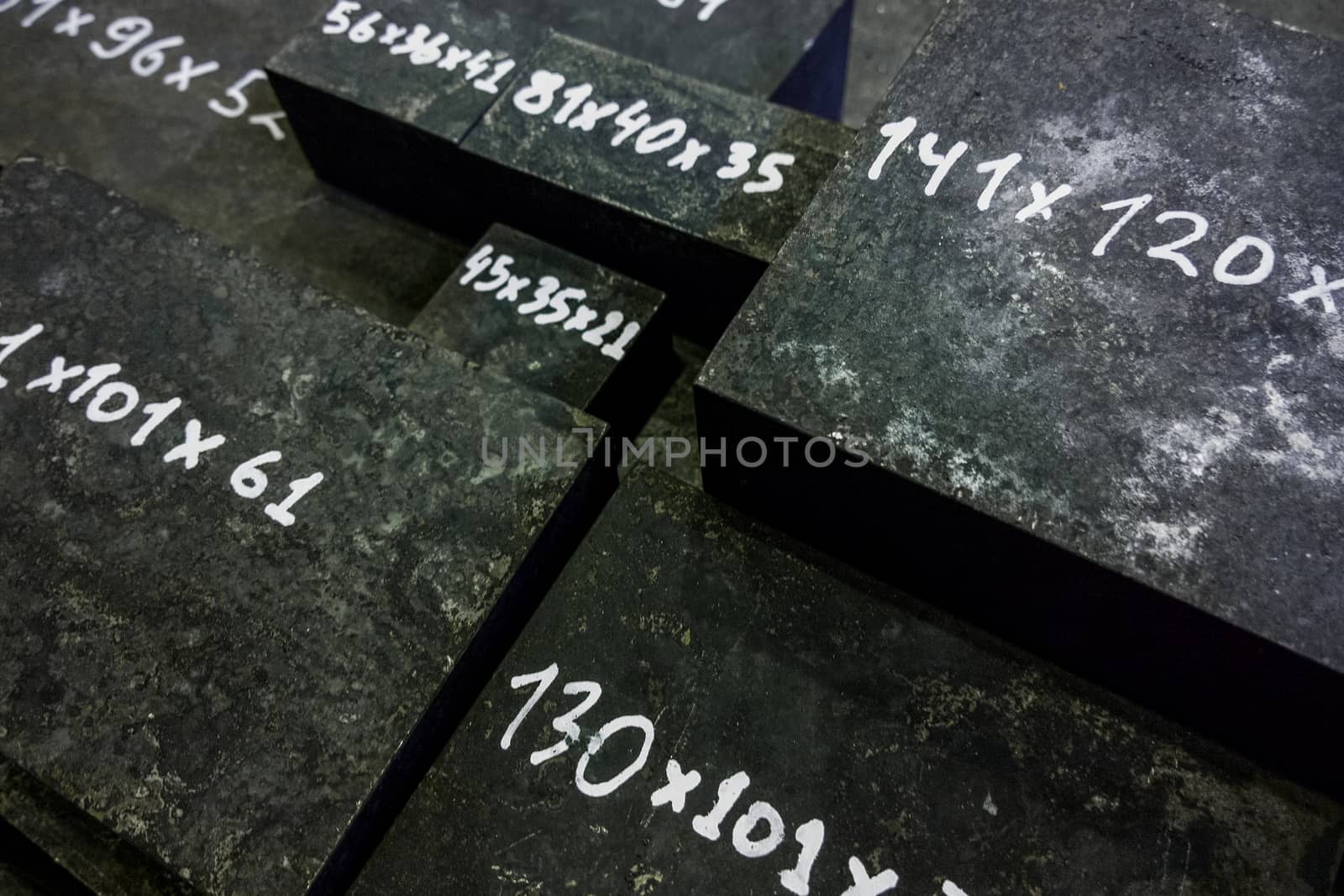 Raw steel bricks after thermal hardening with black slag. Selective focus technique. White numbers - dimensions in mm.