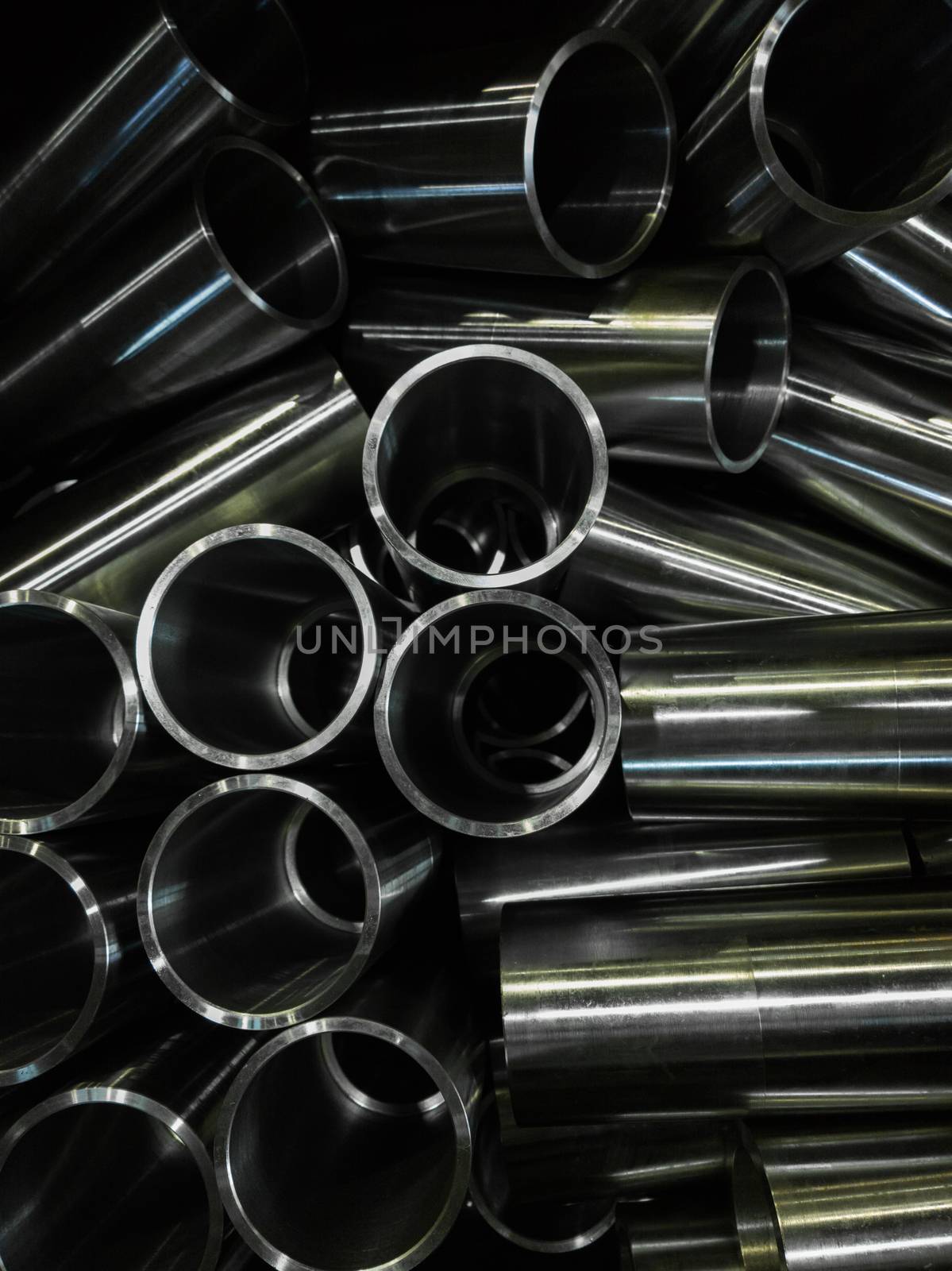 dark industrial background with cnc machined shiny steel pipes - selective focus and lens blur technique