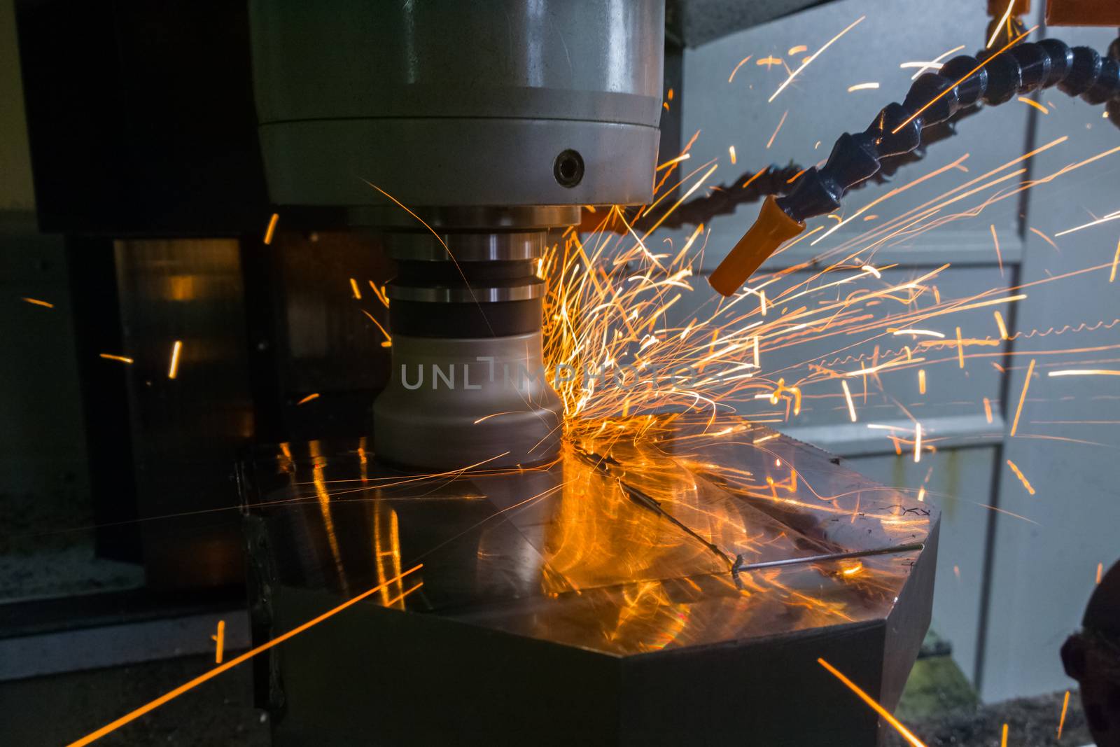 Heavy milling with sparks caused overheating due to wrong cutting feeds and speeds. Safety rules violation in manufacturing process. Selective focus technique in low light conditions.