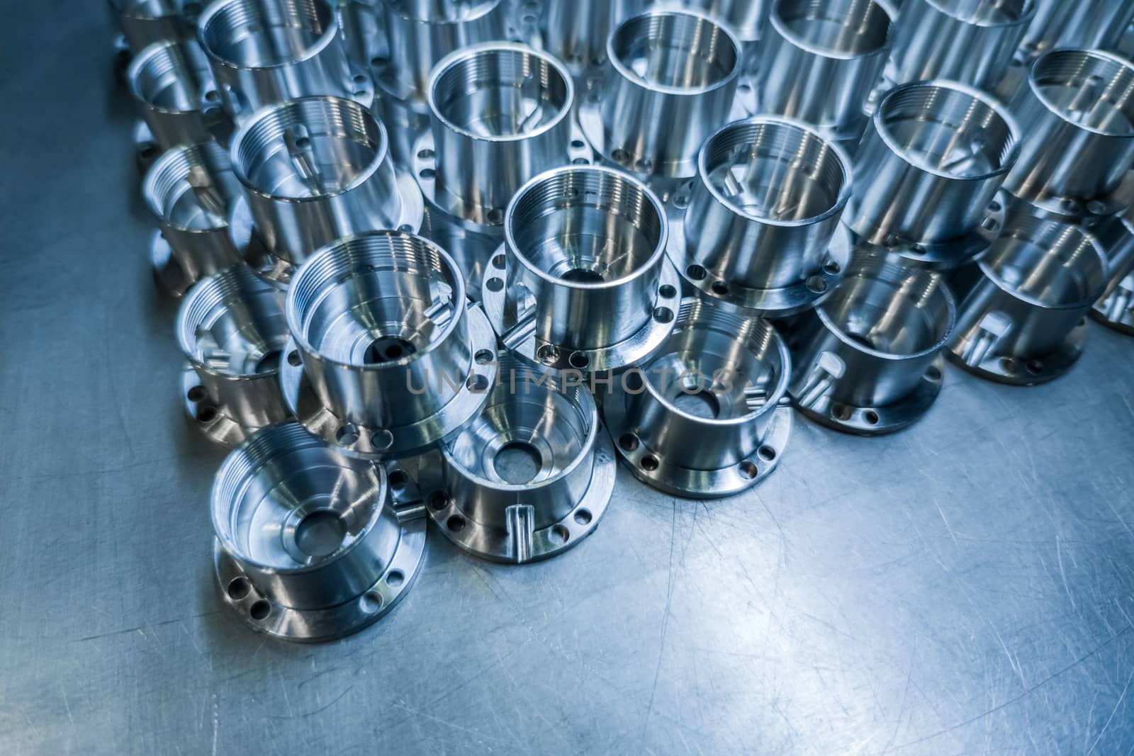 Shiny metal parts after cnc turning, drilling and machining on steel surface with selective focus for industrial background.