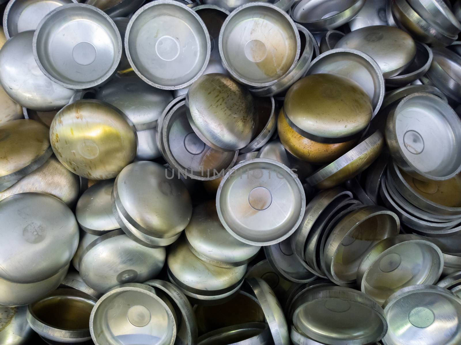 A batch of thick annealed alluminium stamped half-spherical parts. Random piled-up pattern with top-down view.